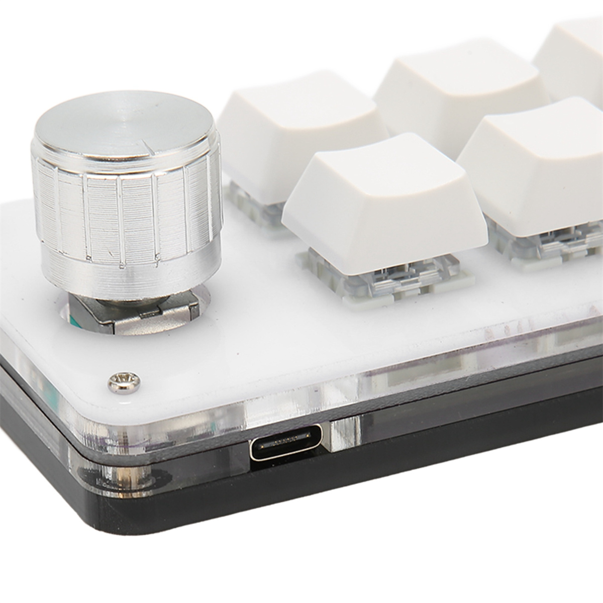 Eine kleine, schwarz-silberne mechanische Tastatur mit weißen Tastenkappen und einem Knopf.