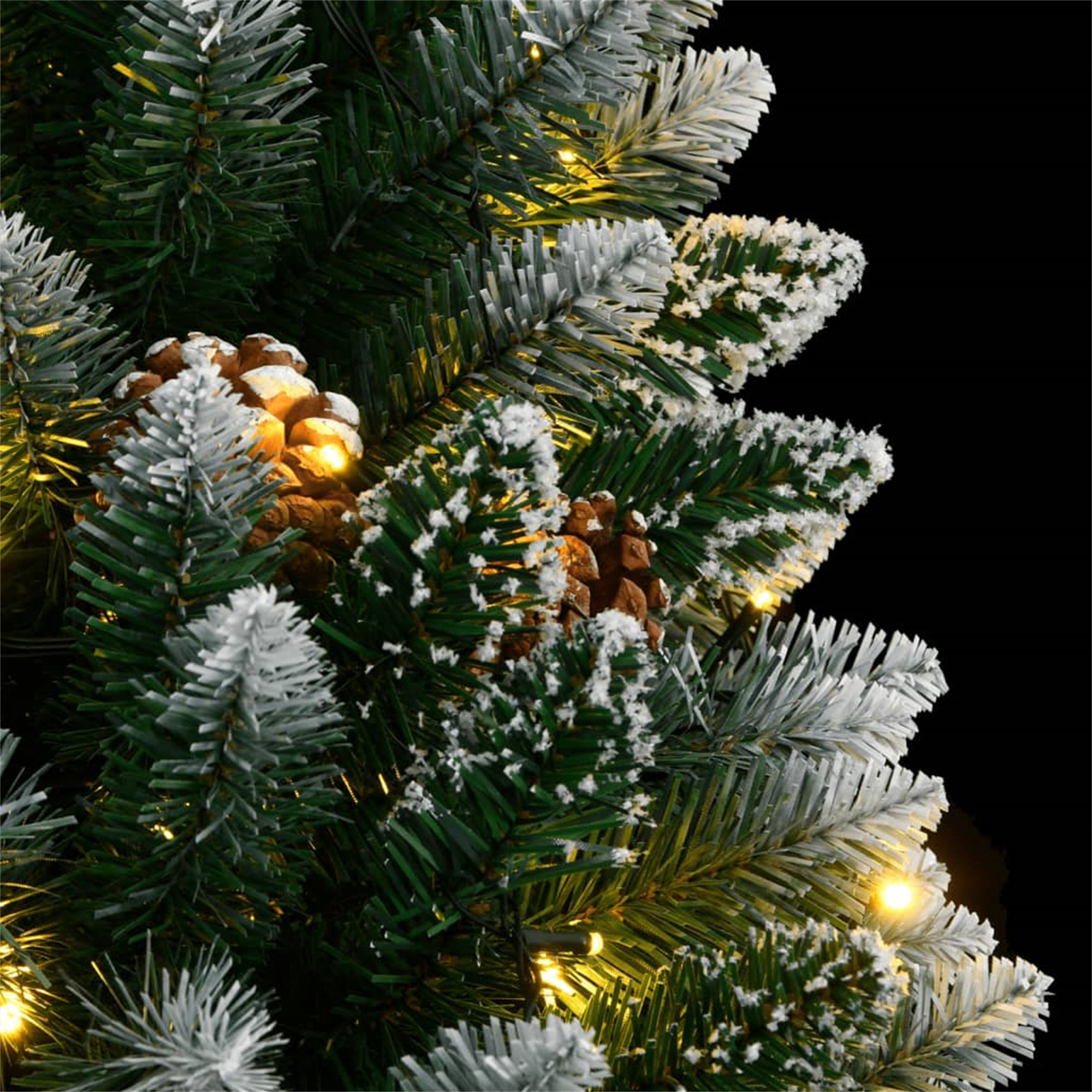Nahaufnahme eines verschneiten Kiefernbaums mit Tannenzapfen und warmgelben Lichtern.