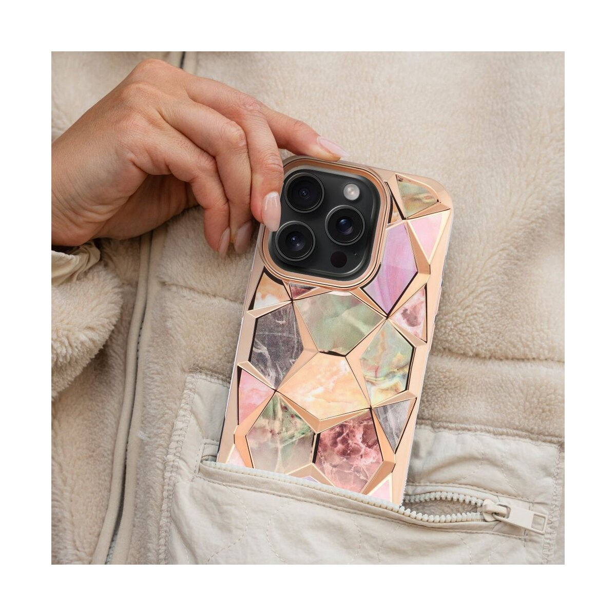 Una mano che tiene una custodia per telefono con un design a mosaico. La custodia è dorata e presenta un motivo geometrico.