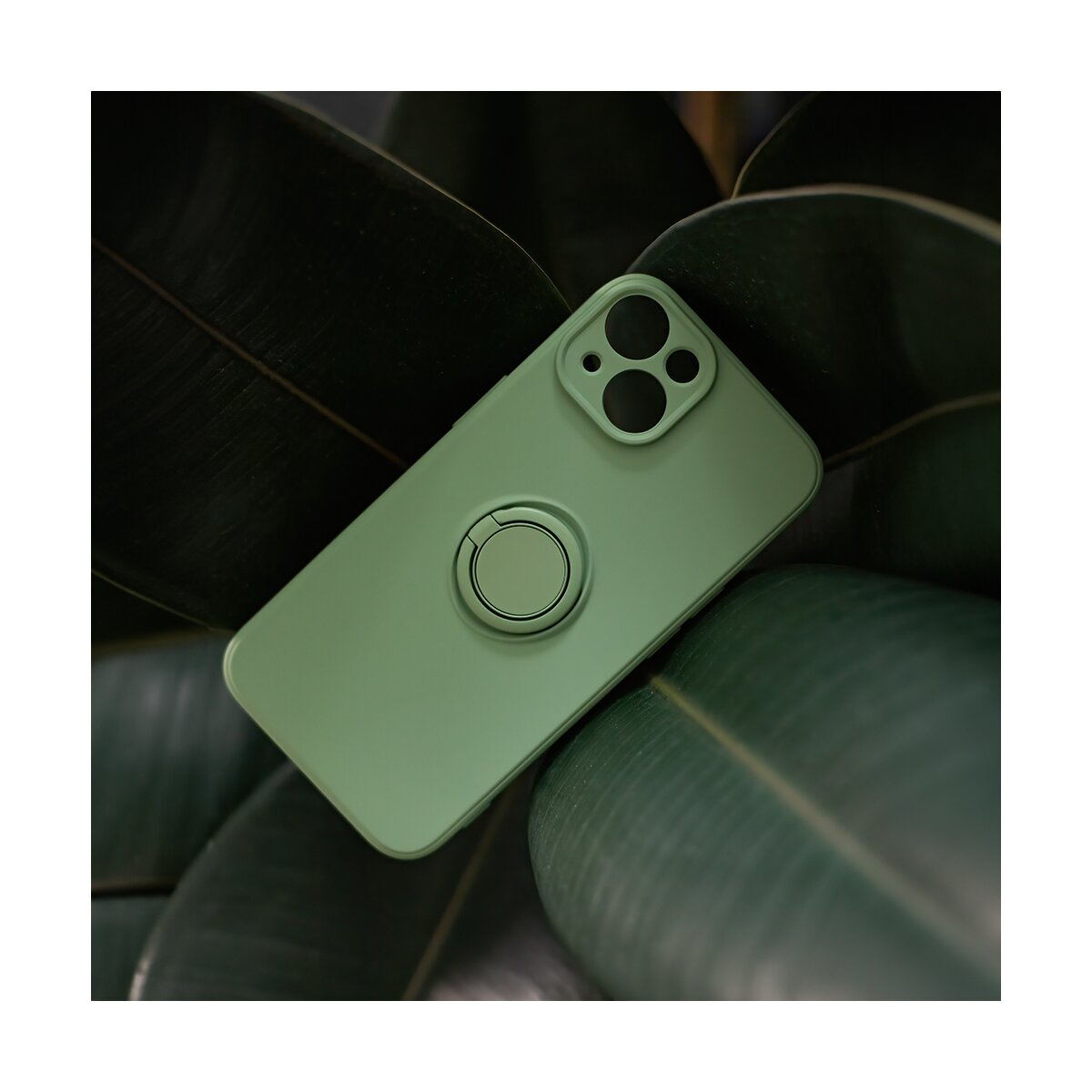 Custodia verde per telefono con anello, contro grandi foglie. Primo piano.