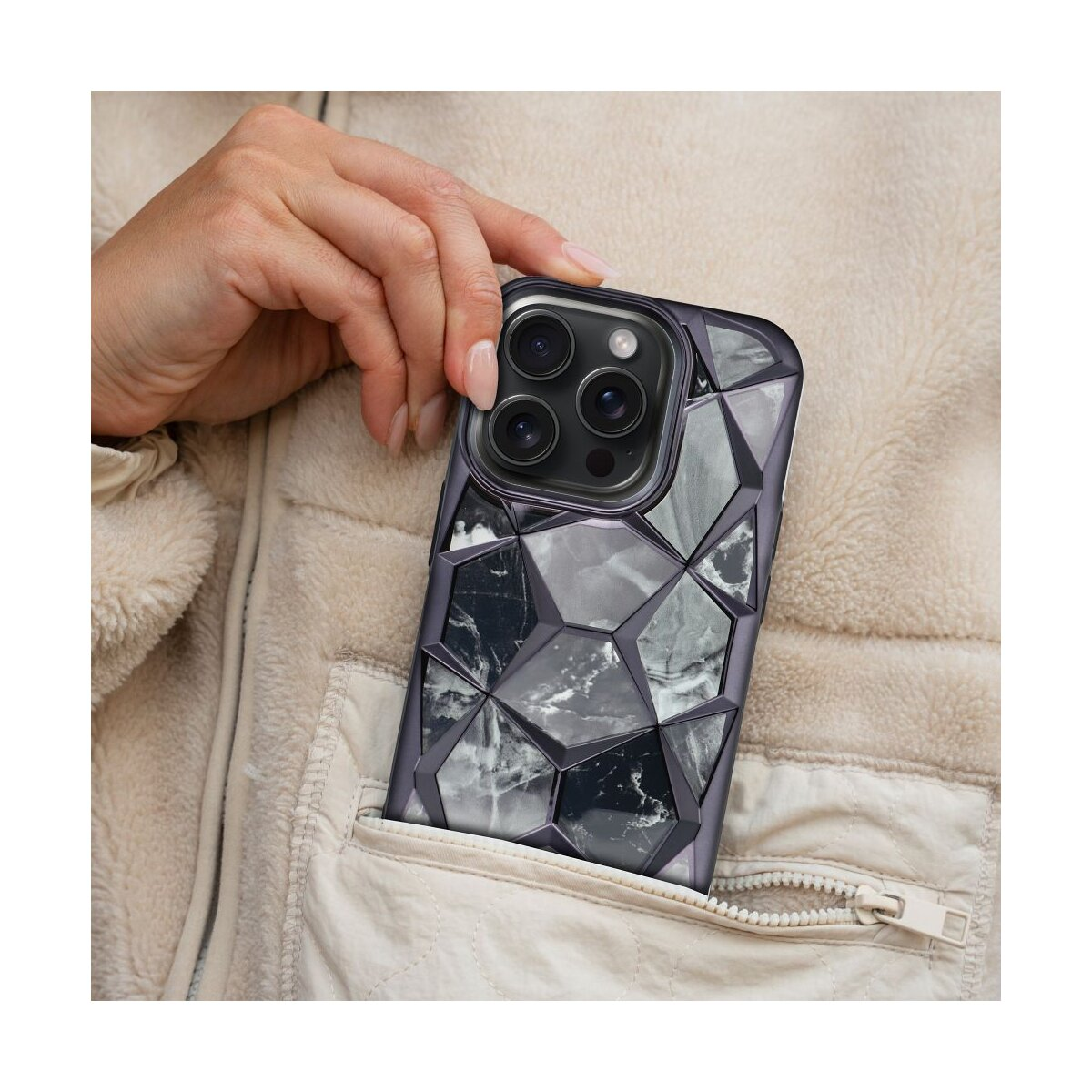 Una mano tiene un telefono in una custodia fantasia. La custodia mostra un disegno geometrico.