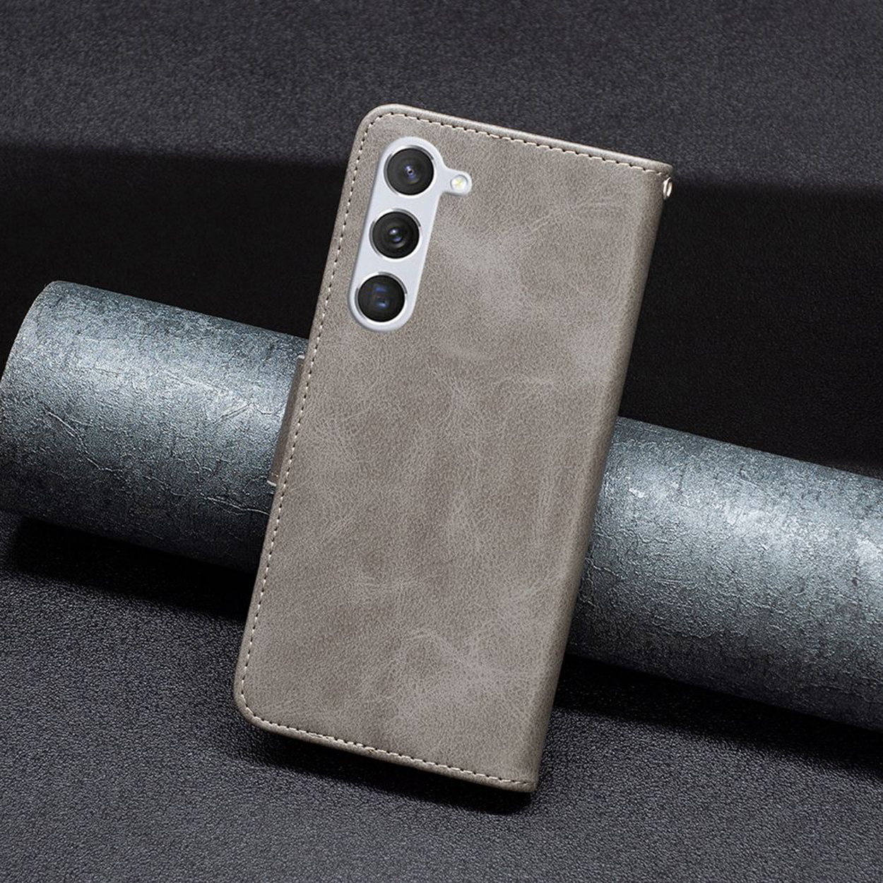 Grijze leren telefoonhoes met de camera van de telefoon zichtbaar. De hoes is gesloten.