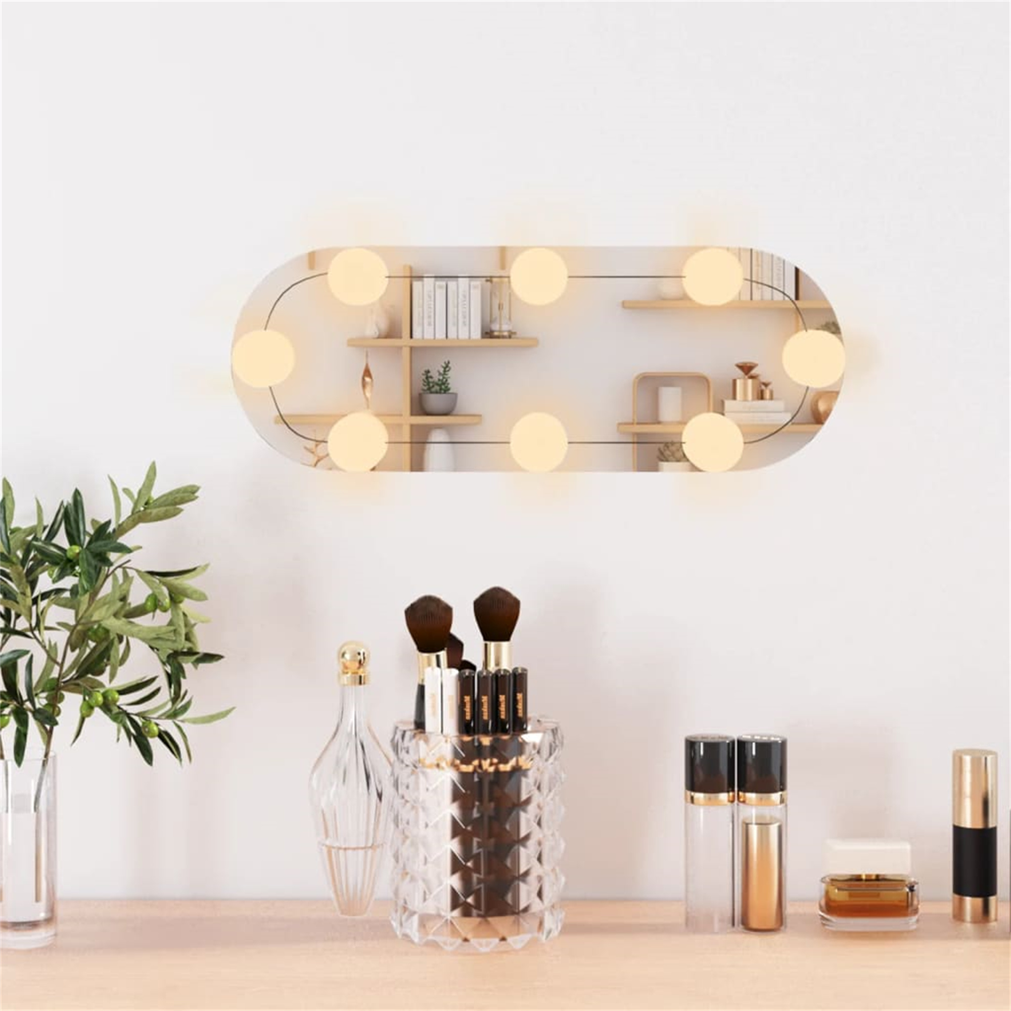 Ein beleuchteter ovaler Spiegel an einer Wand mit Make-up-Pinseln, Parfums und anderen Schönheitsprodukten auf einem Tisch.