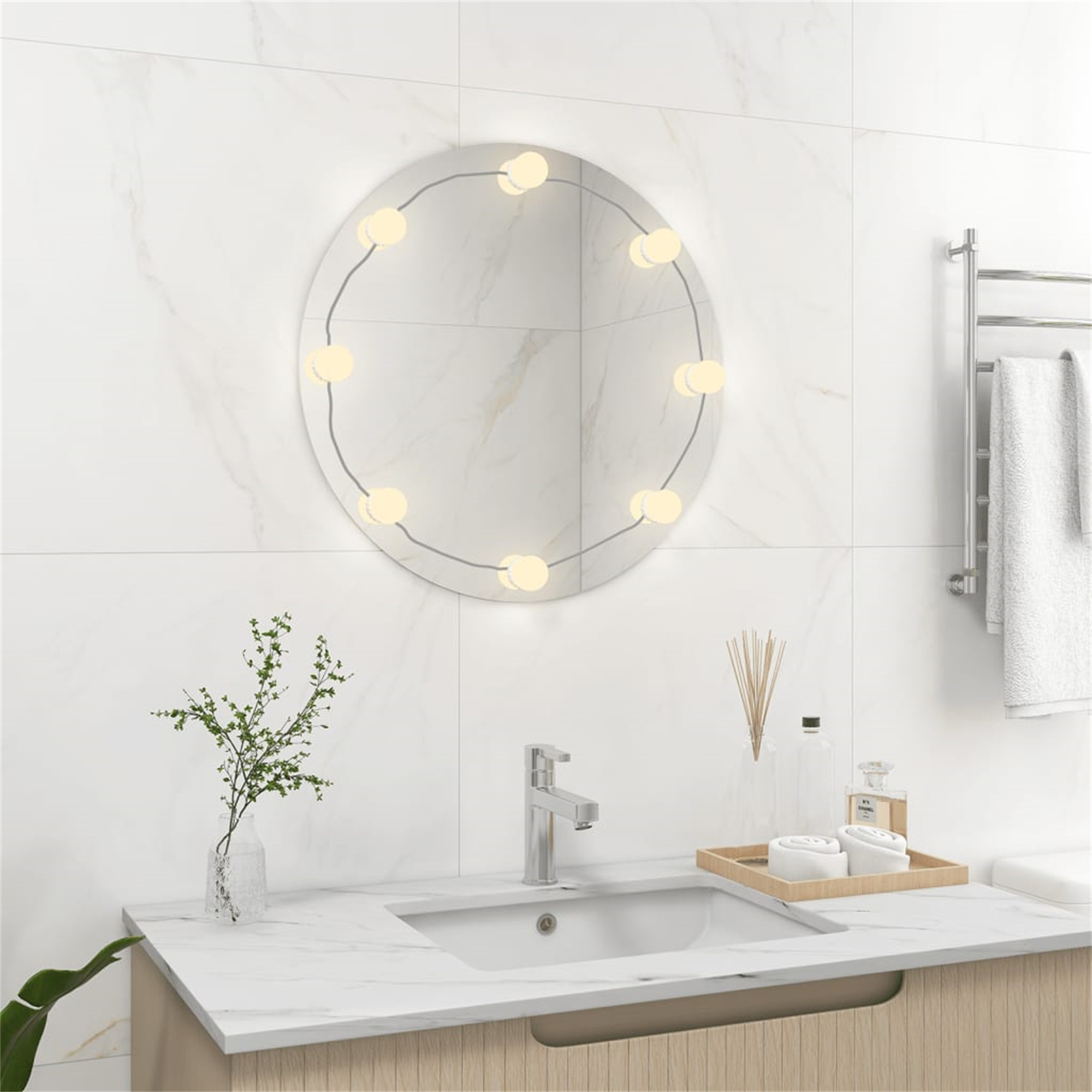 Badezimmer mit rundem Spiegel mit Lichtern, Waschbecken und Dekoration. Handtuchhalter sichtbar.