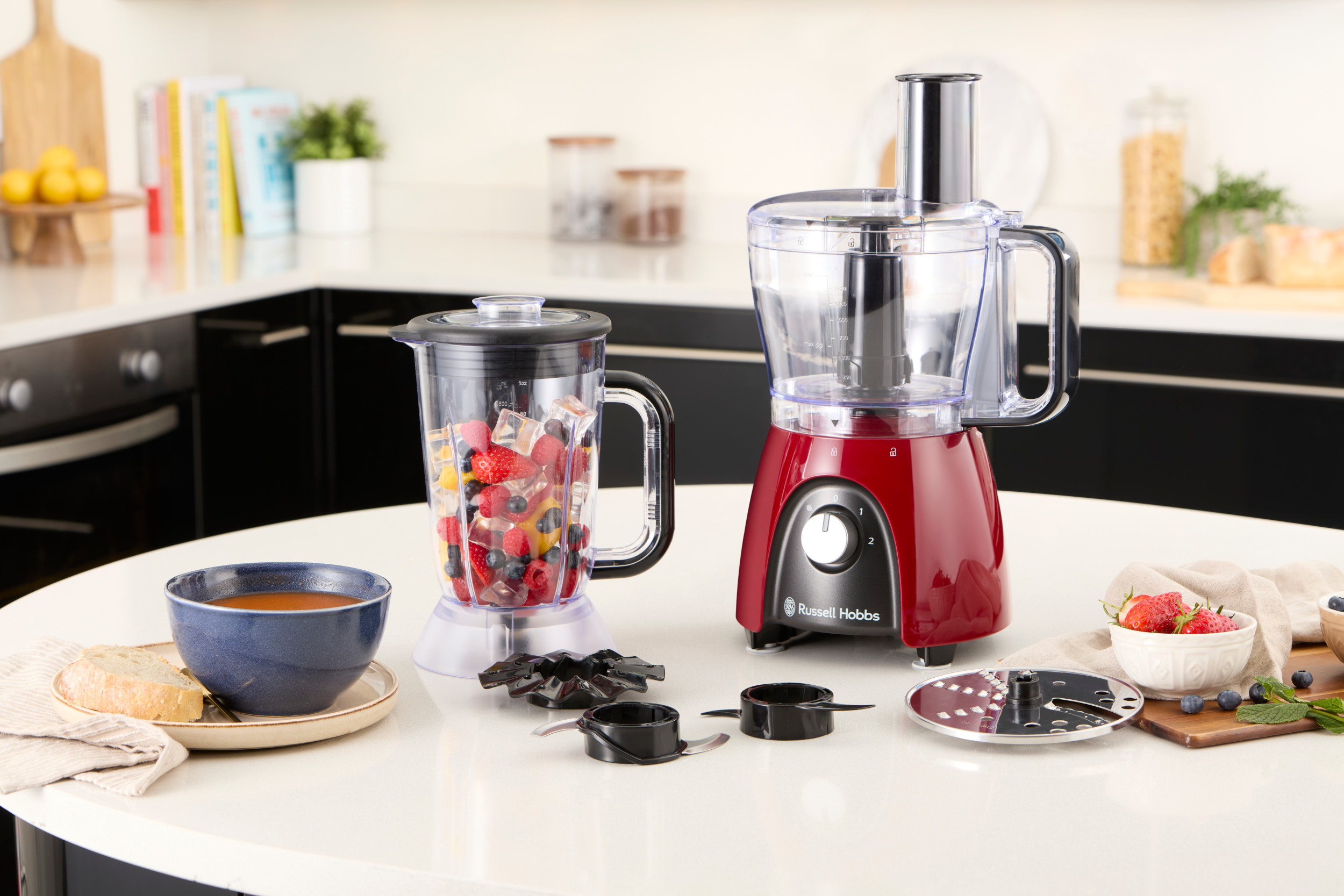 Piano di lavoro della cucina con frullatore, robot da cucina, ciotola di zuppa e ingredienti.