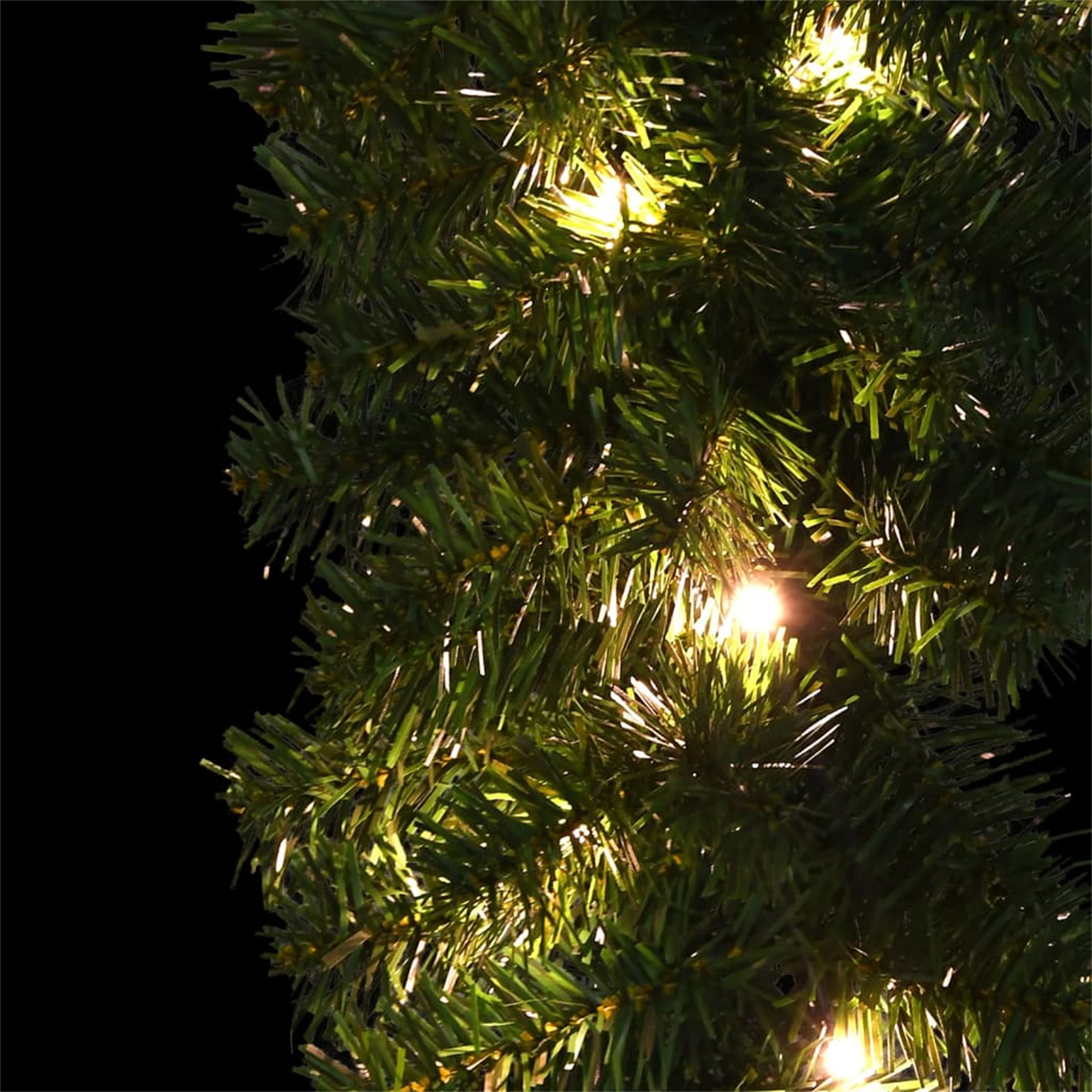 Nahaufnahme einer Weihnachtsbaumgirlande mit Lichtern und dunklem Hintergrund.