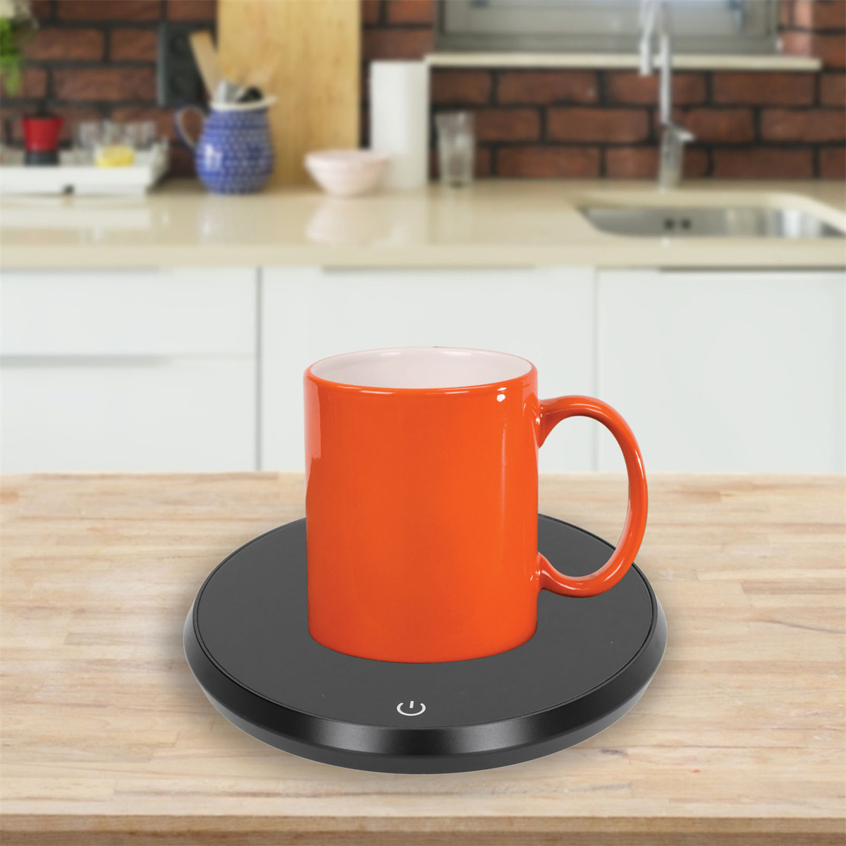 Orangener Becher auf einem schwarzen Tassenwärmer auf einer Holzoberfläche in der Küche.