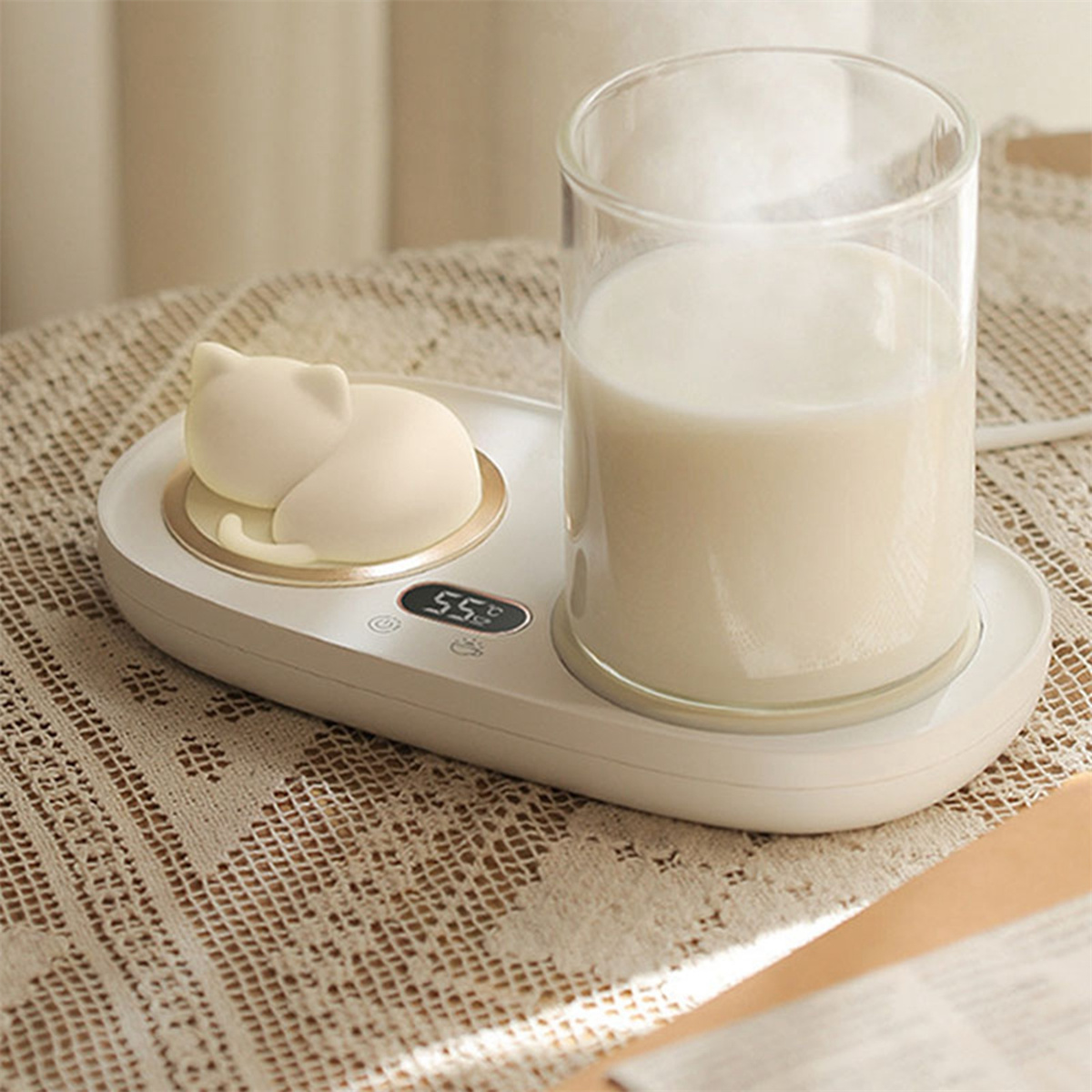 Weißer katzenförmiger Wärmer mit einem Glas Milch. Auf einem Tisch mit Spitzentuch.