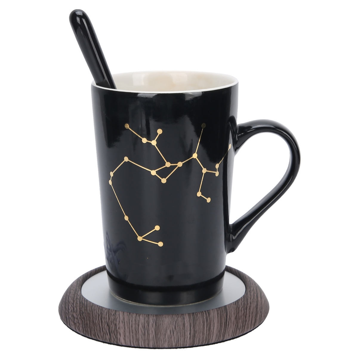 Eine schwarze Tasse mit Sternbild-Design und einem Löffel. Sie steht auf einem Holzuntersetzer.
