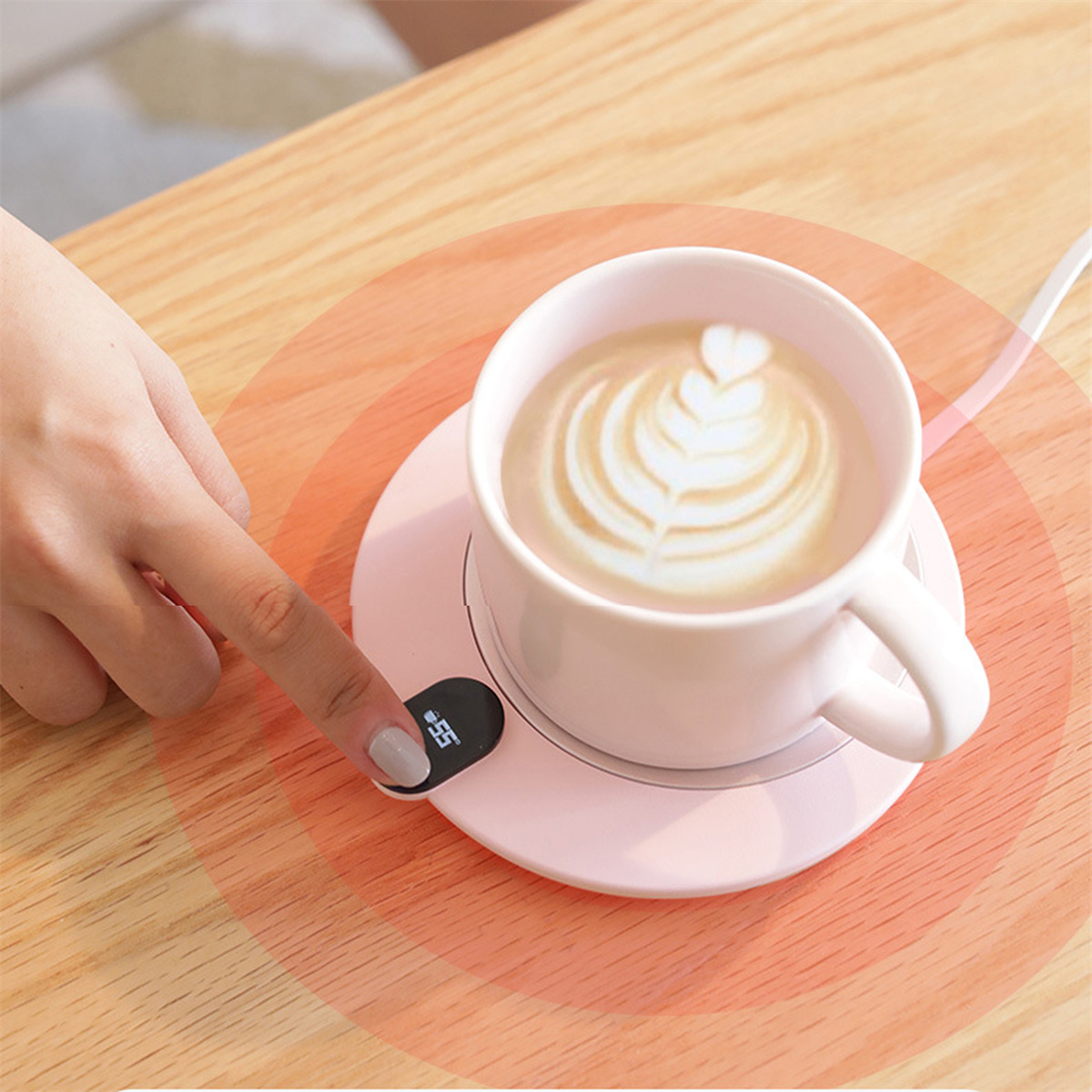 Rosa Kaffeetasse auf einem Wärmer mit einem Finger, der den Knopf drückt.
