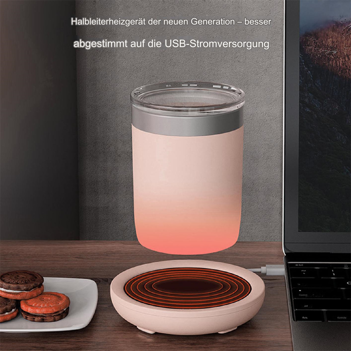 Eine rosa Tassenwärmer mit einer Tasse, Keksen und einem Laptop. Der Wärmer steht auf einer braunen Oberfläche.