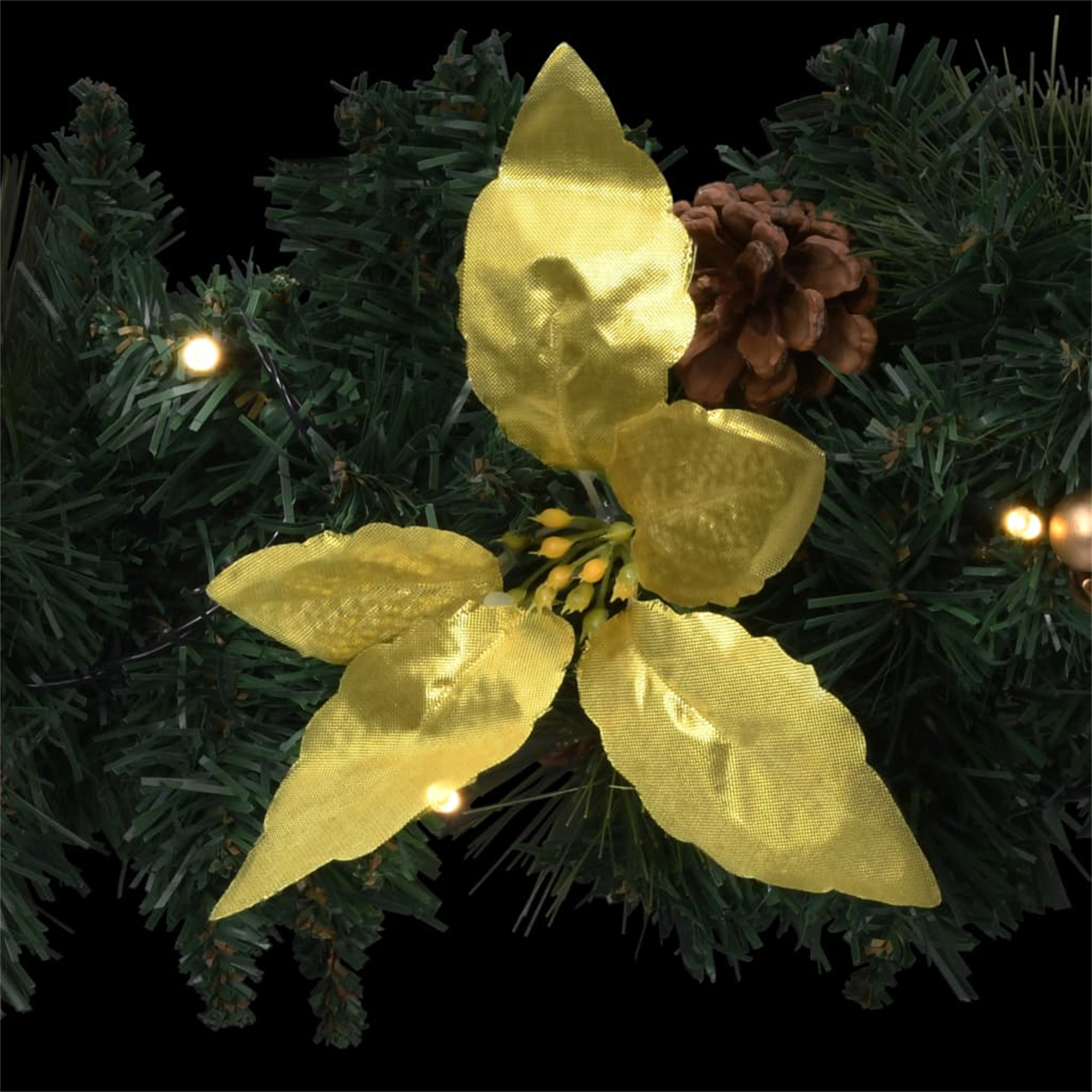 Ein Weihnachtsgirlande mit goldenen Blättern, einem Tannenzapfen und kleinen Lichtern auf schwarzem Hintergrund.
