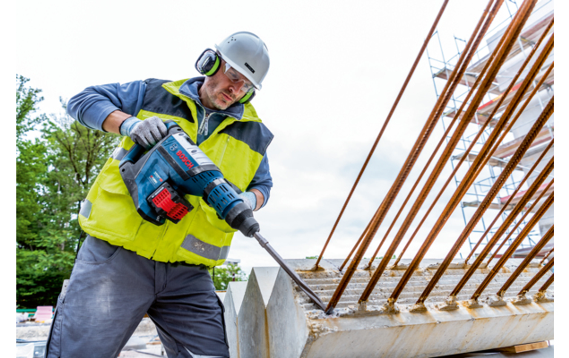 Trabajador de la construcción usando un martillo neumático en hormigón, con equipo de seguridad.