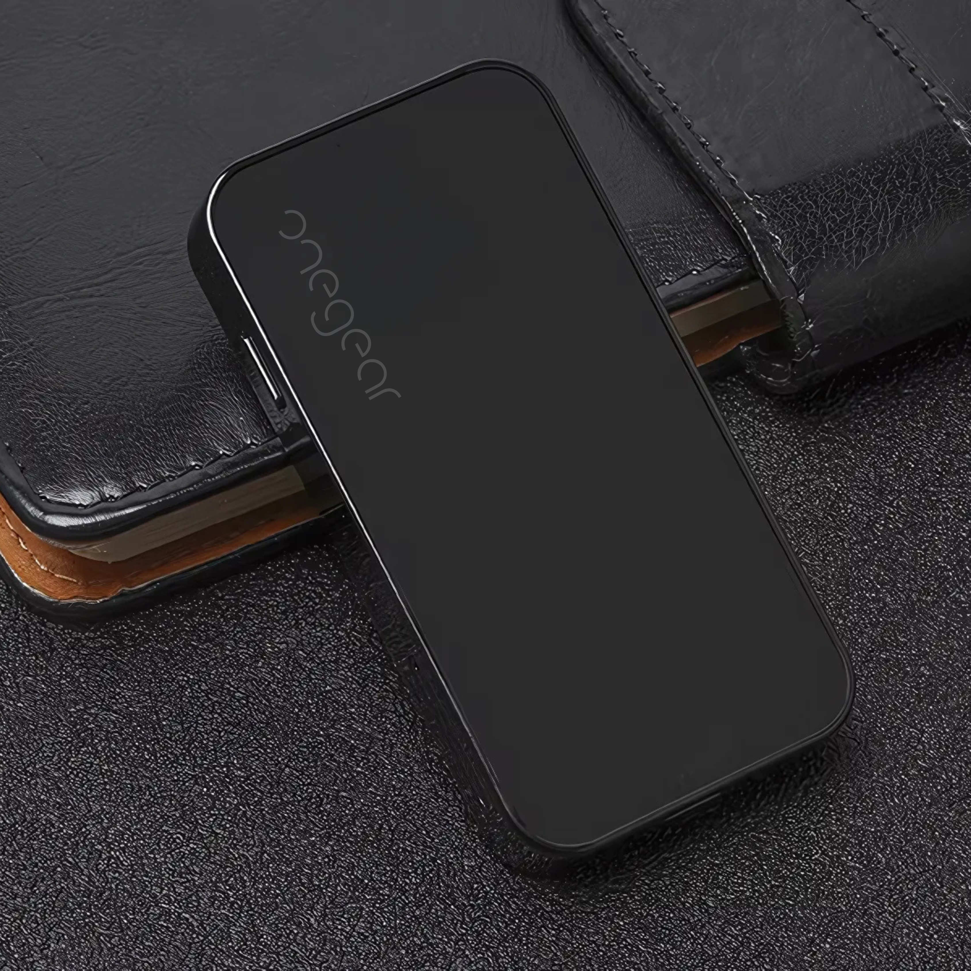 Dispositivo rettangolare nero con il marchio "onegear" su una superficie scura. È un piccolo telefono.