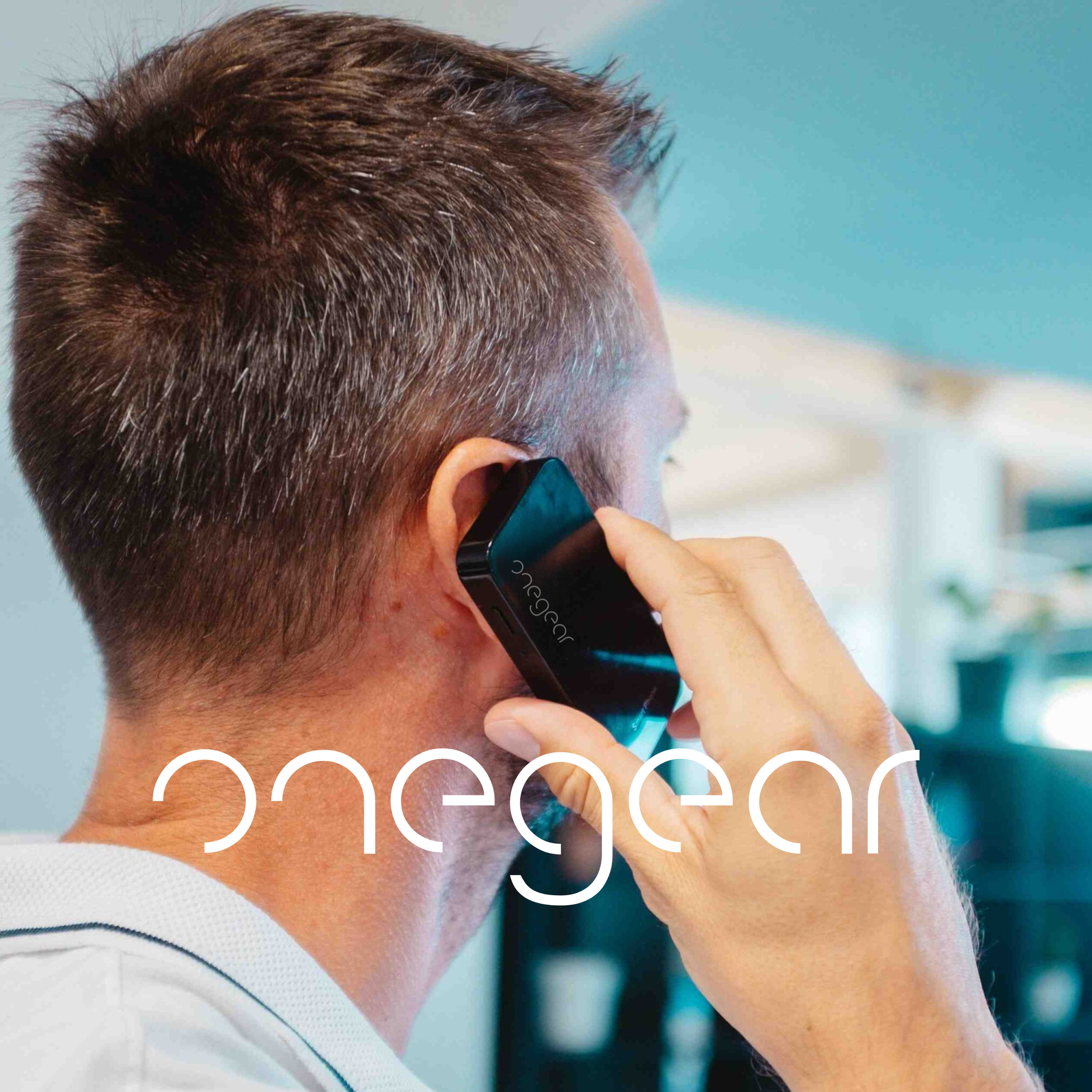Un uomo tiene un telefono nero all'orecchio. Il logo sul telefono dice 'onegear'.