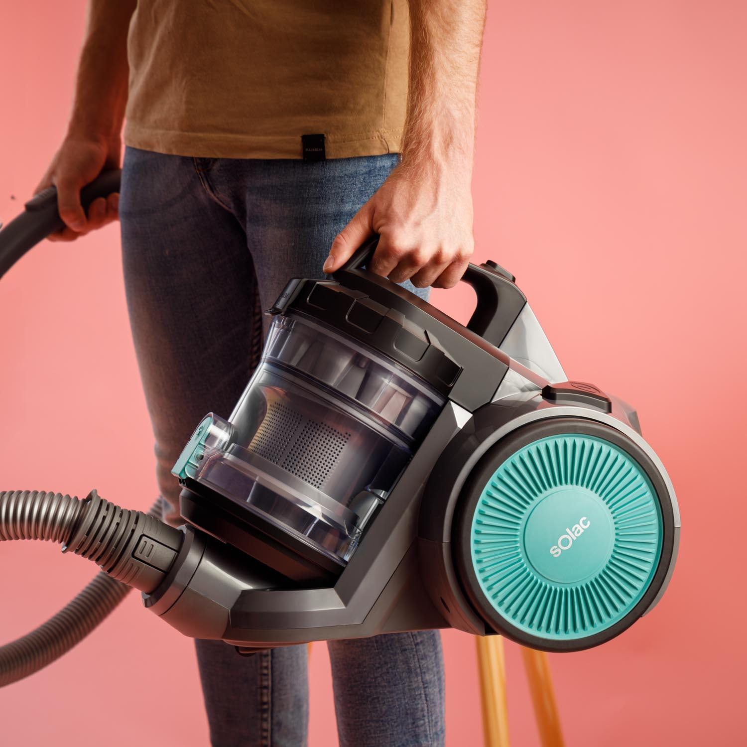Osoba trzymająca odkurzacz Solac. Odkurzacz jest szary i turkusowy.