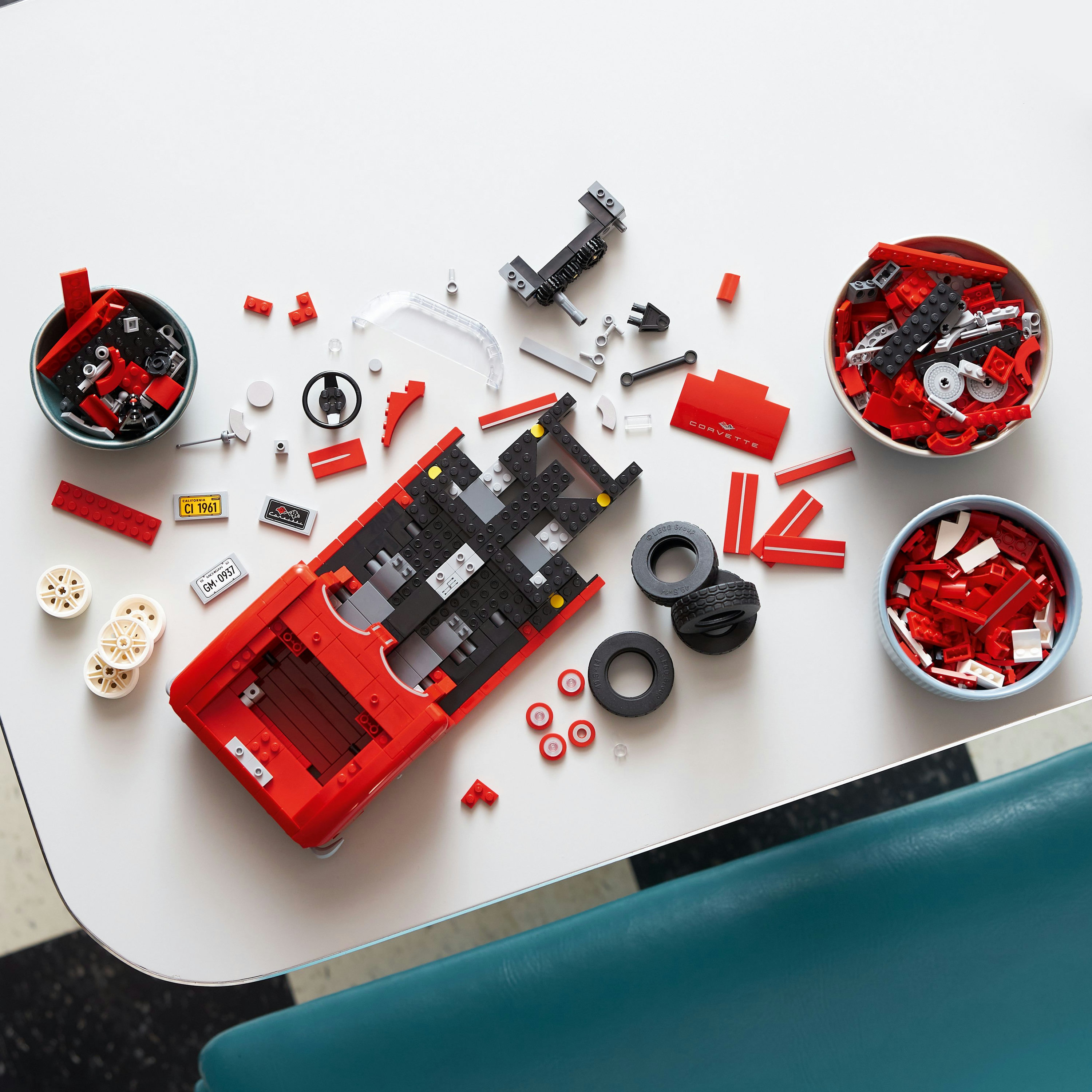 Auto Lego Corvette in fase di assemblaggio su un tavolo, con pezzi in ciotole.