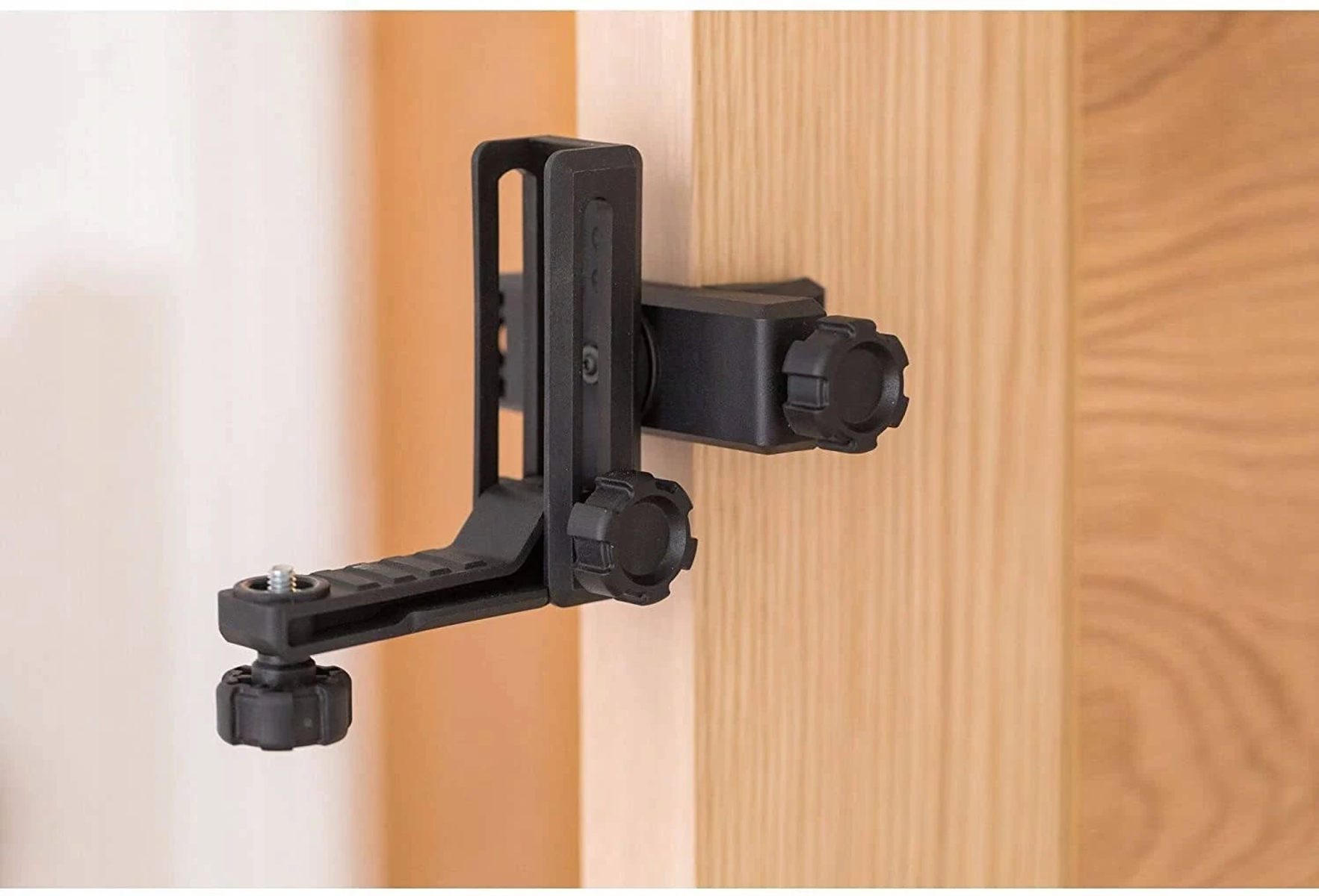 Czarny poziomica przymocowana do drewnianych drzwi. Ma regulowane pokrętła i wspornik.