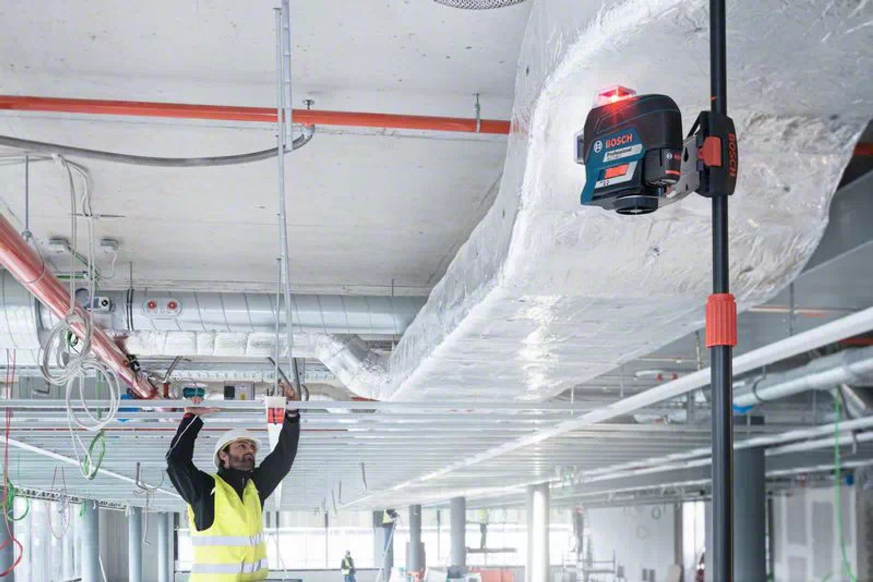 Mężczyzna używa poziomicy laserowej Bosch na budowie.