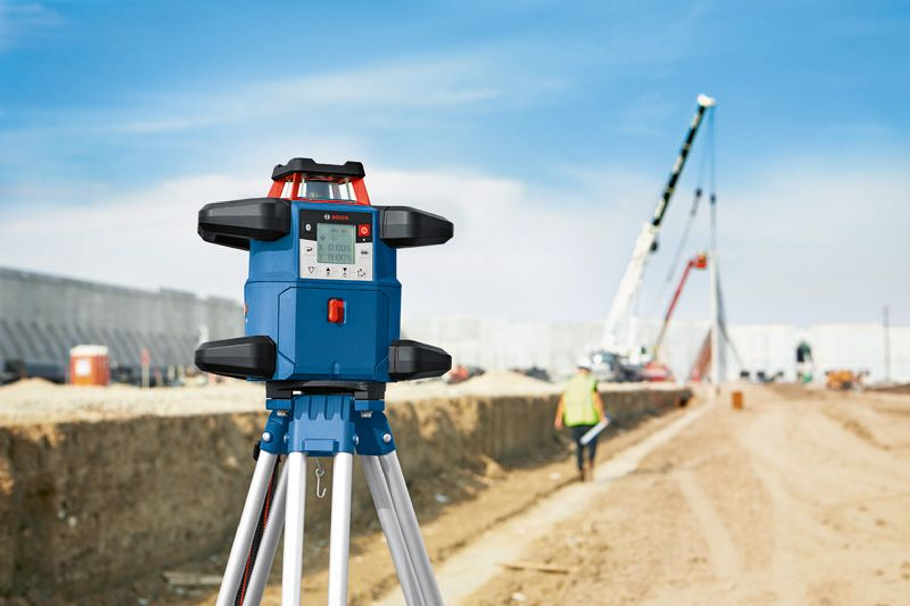 Un nivel láser azul y negro en un trípode en un sitio de construcción.
