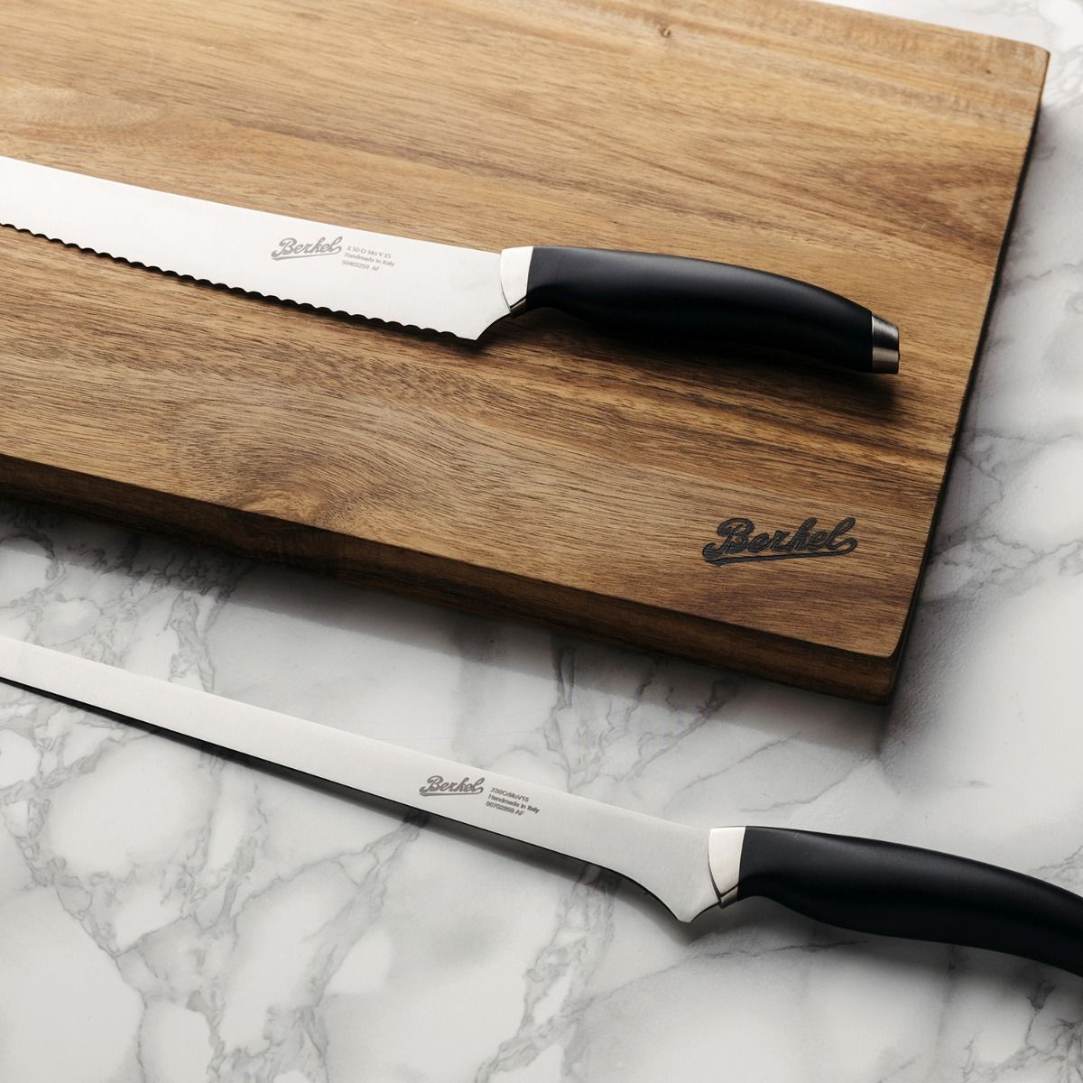 Due coltelli su un tagliere di legno. Uno è un coltello da pane, l'altro è un coltello da intaglio.