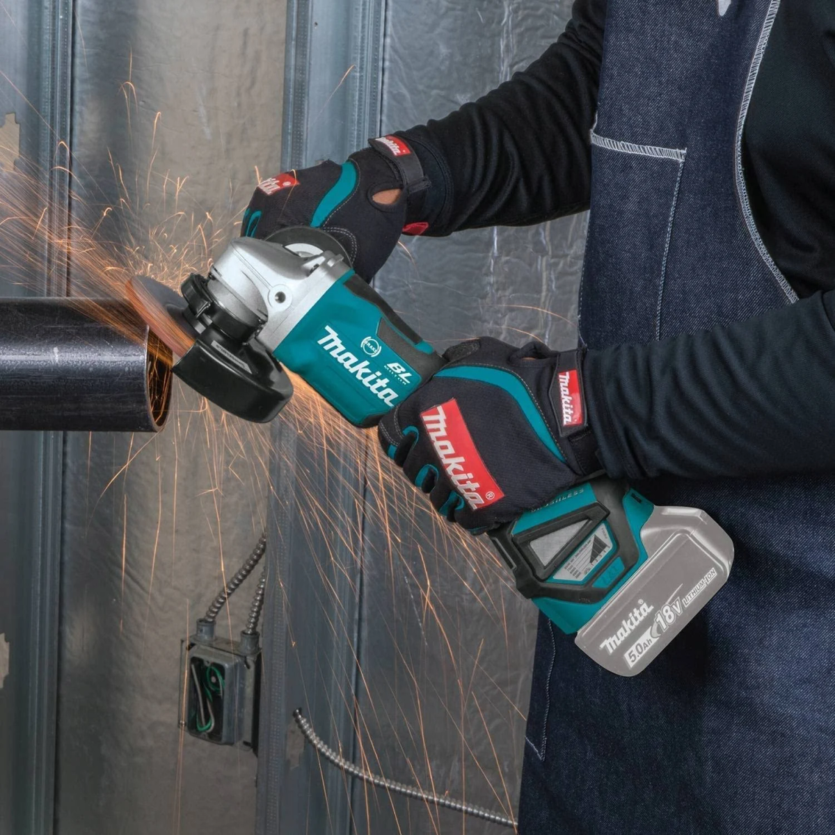 Persona usando una amoladora angular Makita, creando chispas al cortar un tubo metálico.