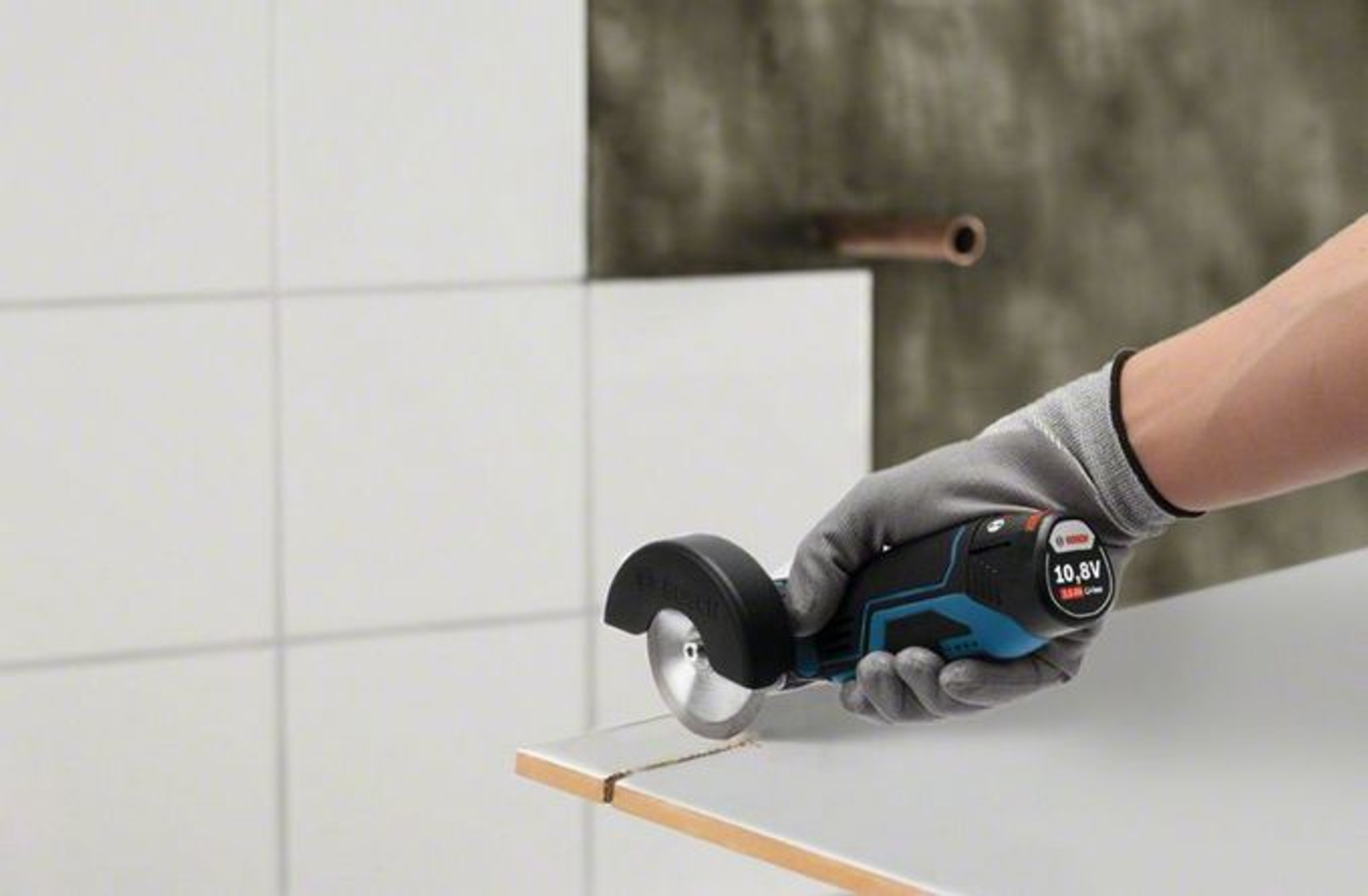 Ręka w rękawicy używa piły do płytek do cięcia płytki.