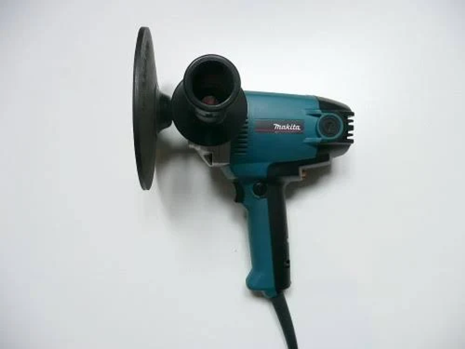 Una lijadora Makita turquesa con mango negro y disco de lijado redondo.