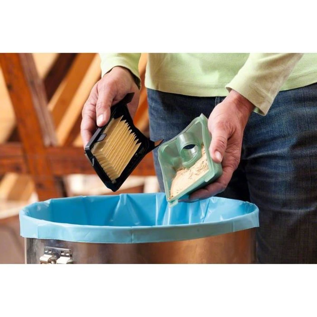 Mains vidant un filtre d'aspirateur dans un sac poubelle bleu, sciure visible.