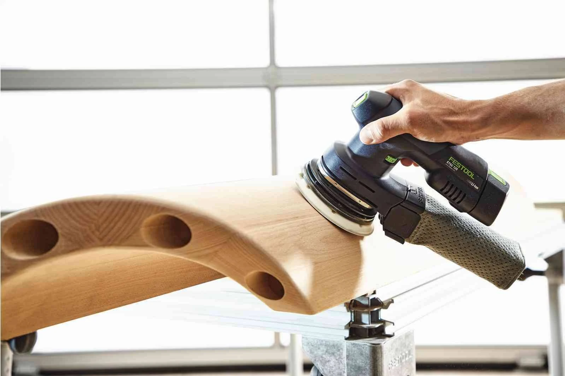 Persona lijando una superficie curva de madera con una lijadora Festool.