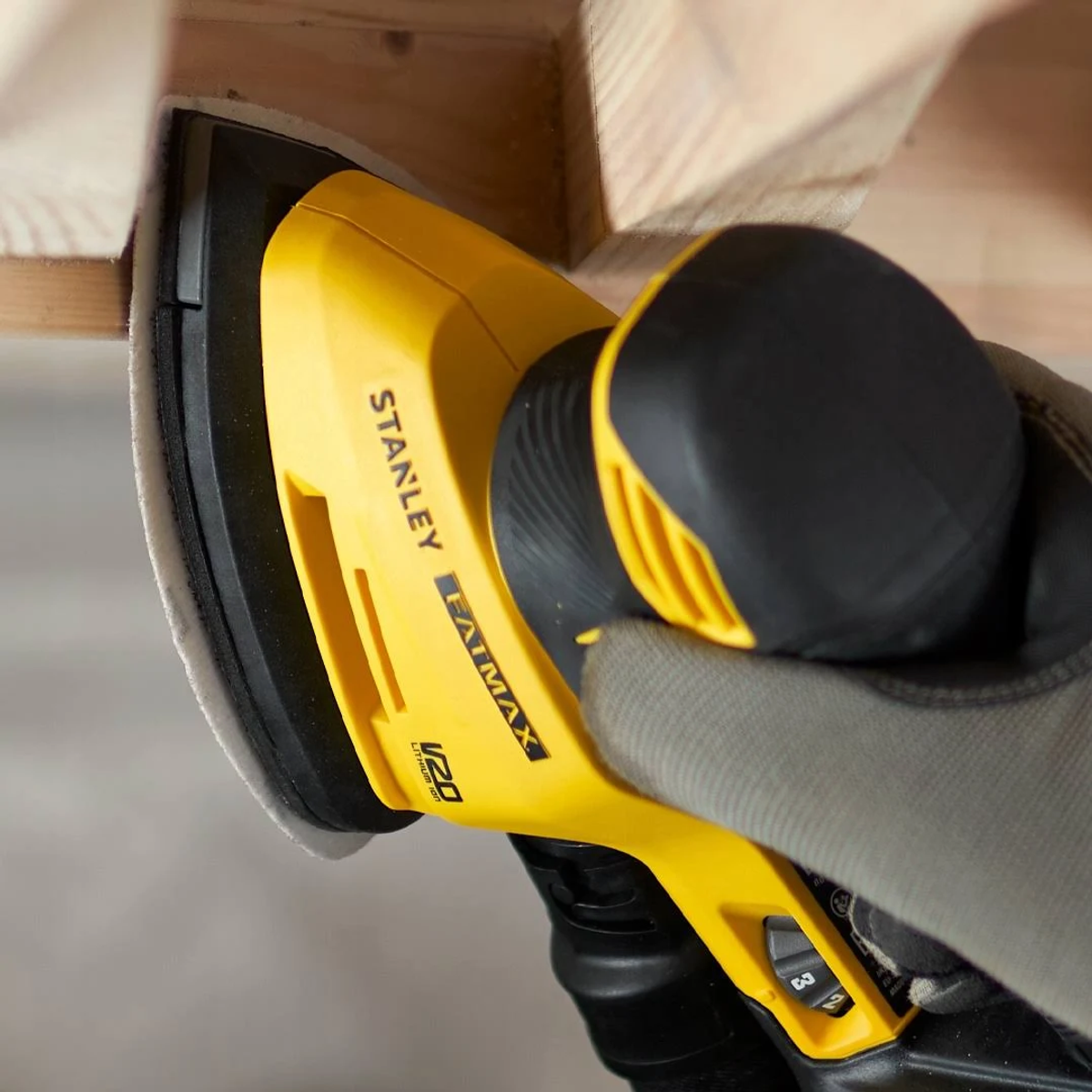 Una lijadora Stanley Fatmax amarilla lijando una superficie de madera.