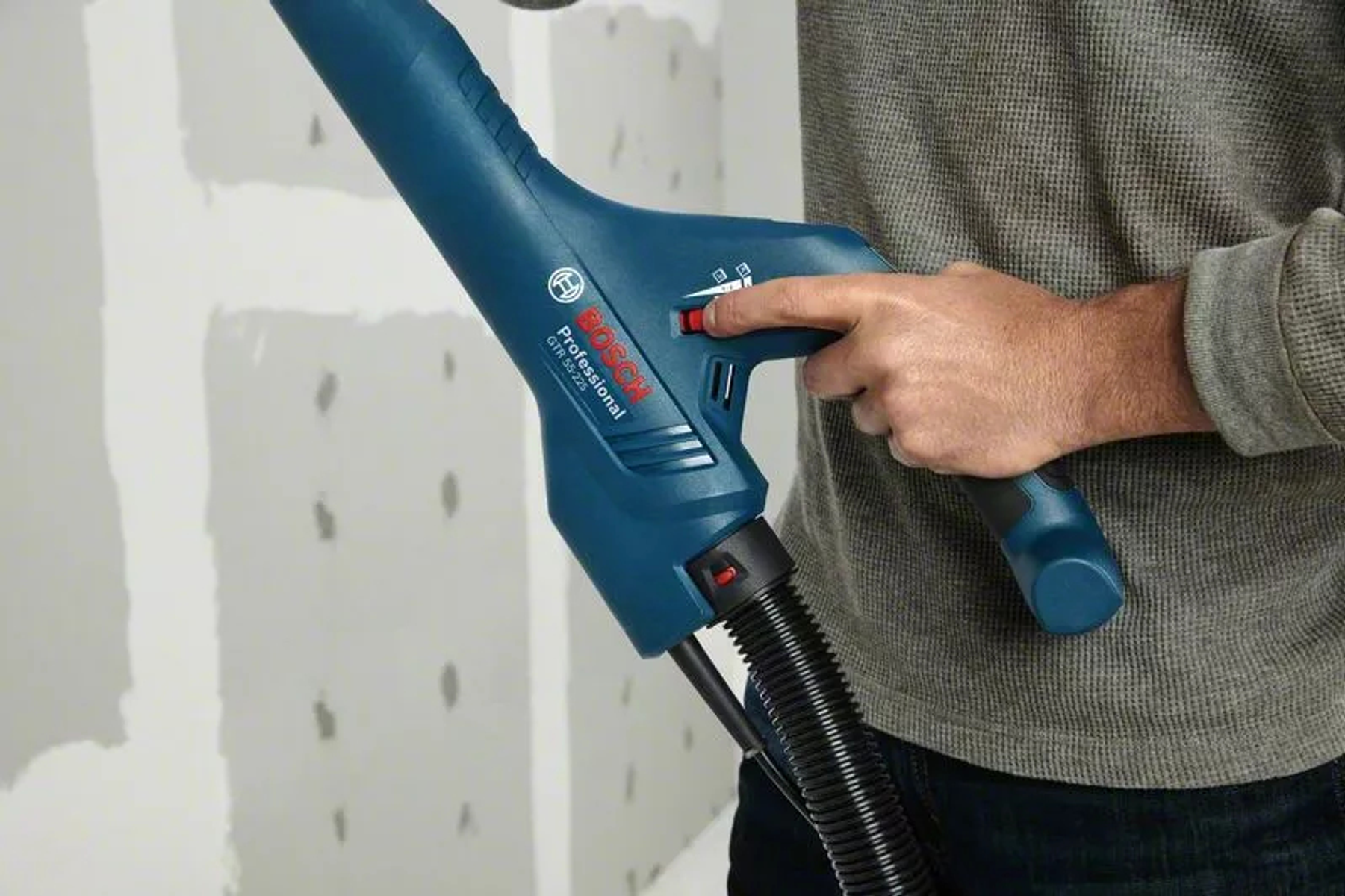 Ponceuse murale Bosch Professional, bleue et noire, en cours d'utilisation.