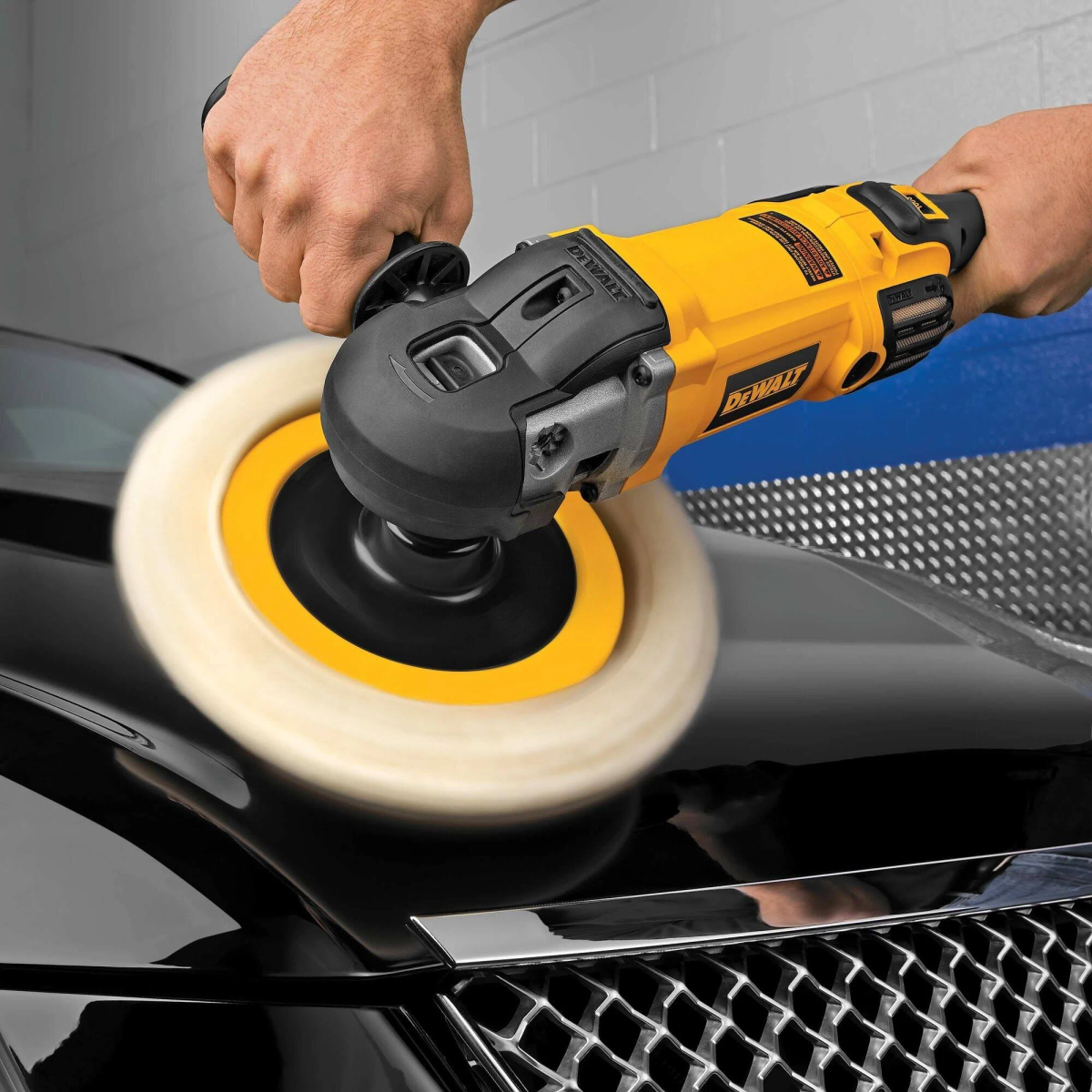 Personne polissant une voiture noire avec une polisseuse DeWalt jaune et noire et un tampon blanc.