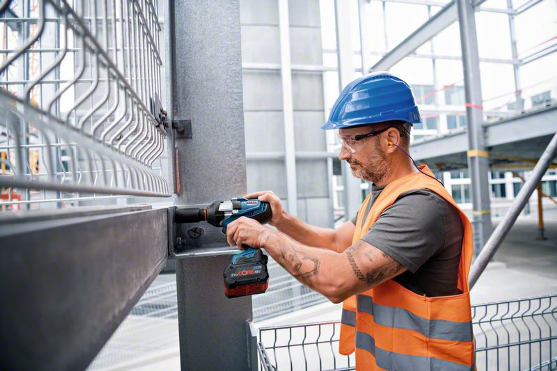 Bir inşaat alanında Bosch darbeli anahtar kullanan, güvenlik ekipmanı giyen adam.