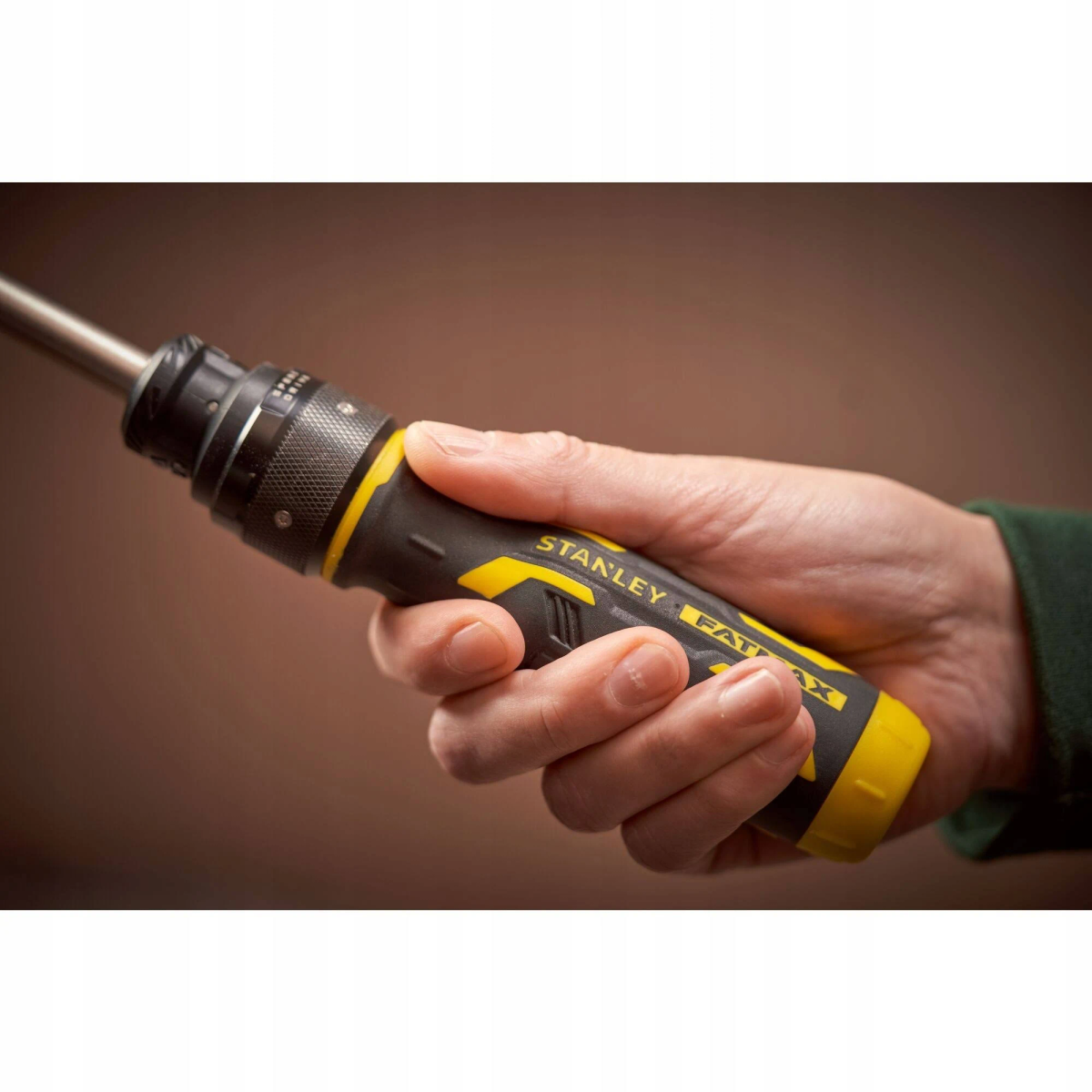 Una mano sostiene un destornillador Stanley FatMax. Es negro y amarillo.
