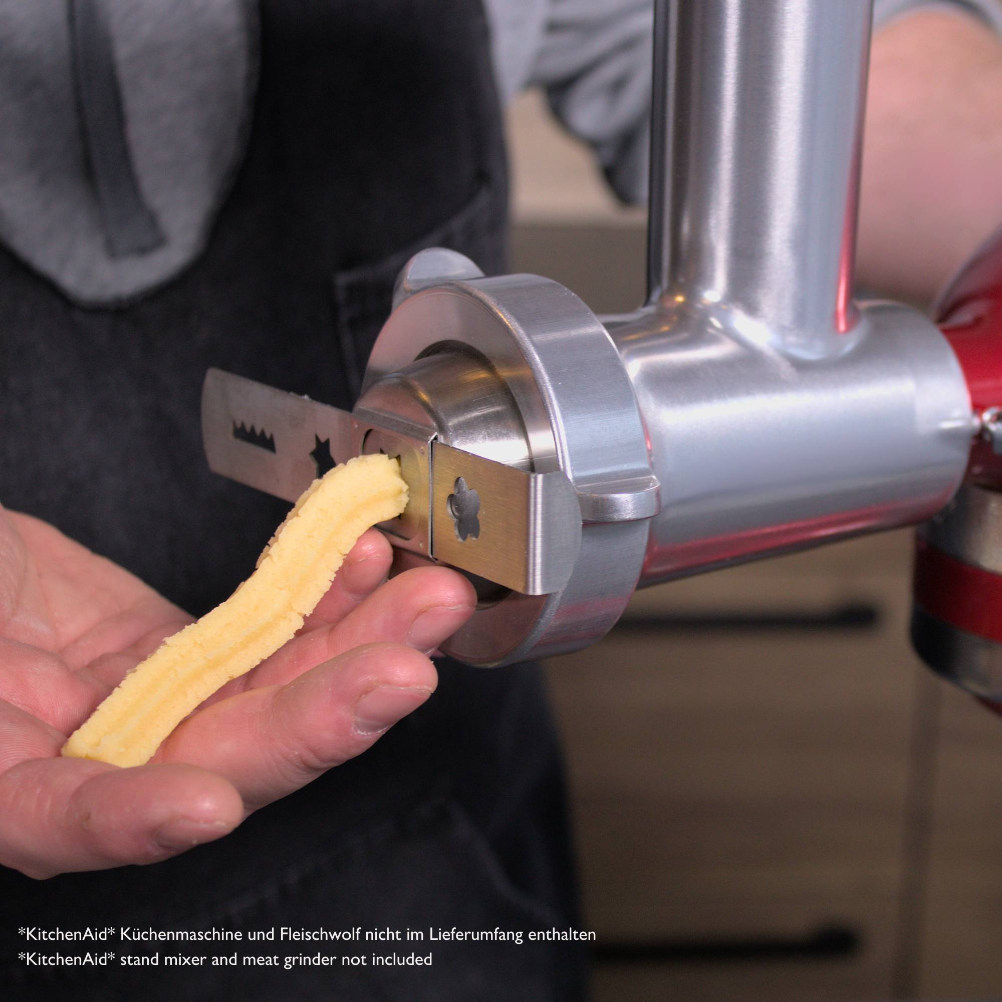 KitchenAid-Mixer mit Fleischwolf-Aufsatz, der ein gelbes Lebensmittel produziert.