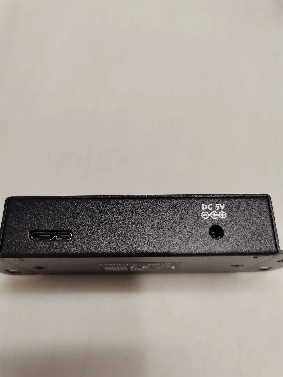 Un hub USB argento con quattro porte USB, un cavo bianco e un connettore USB.