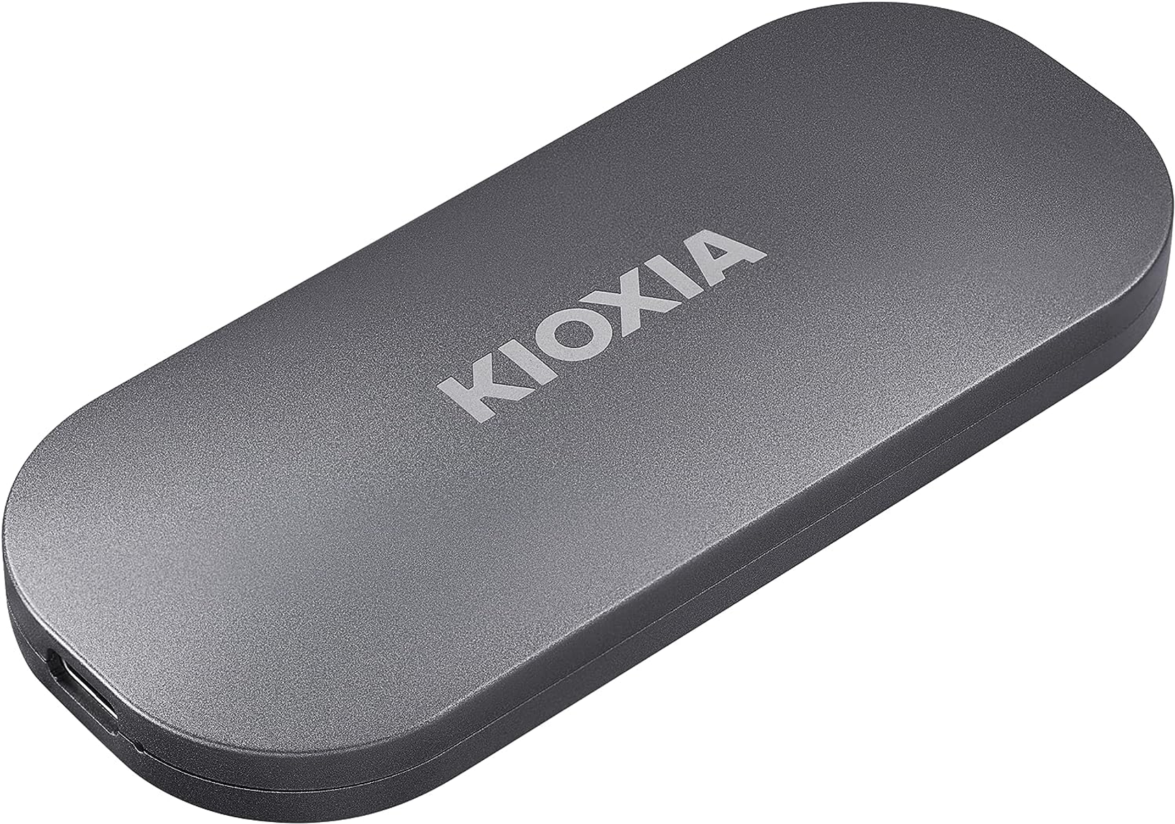 Szary zewnętrzny dysk twardy KIOXIA leżący na białej powierzchni.