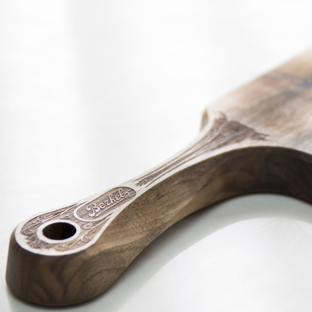 Manico in legno con marchio Berkel, con intagli decorativi, su sfondo bianco.