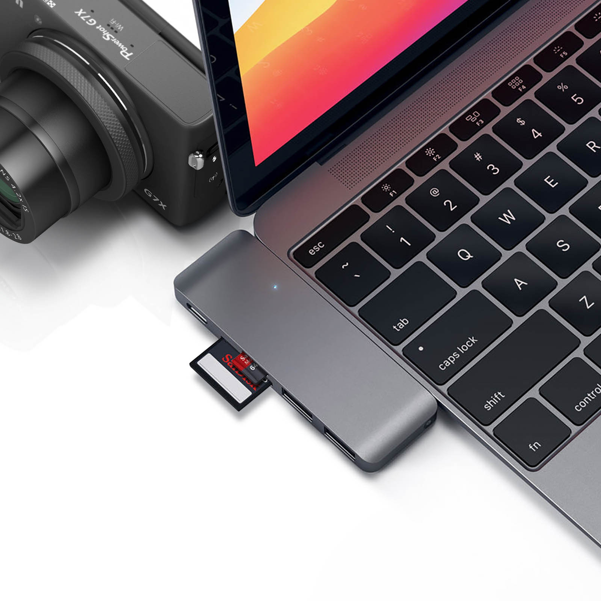 Laptop mit Kartenleser, Kamera und eingesetzter SD-Karte. Alles auf weißer Oberfläche.