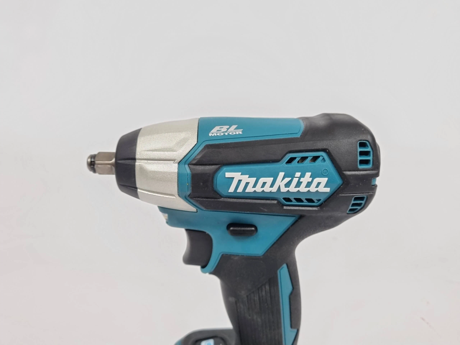 Un atornillador de impacto Makita negro y verde azulado. Fondo blanco.