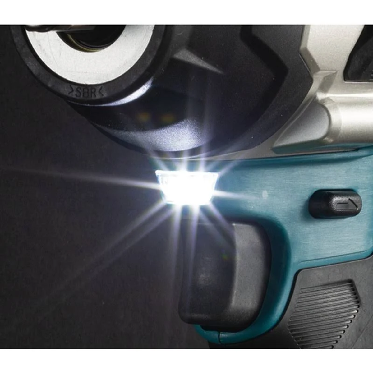 Primer plano de un taladro con luz brillante. La herramienta es negra y verde azulado.