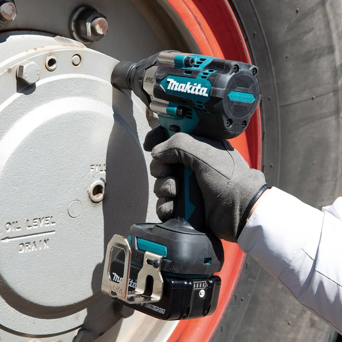 Persona usando una llave de impacto Makita en una rueda grande. Turquesa y negro.