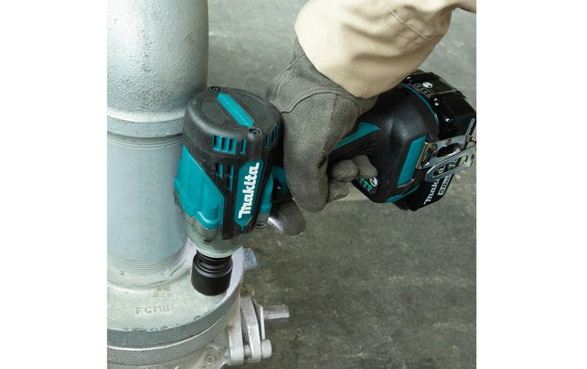 Robotnik używa turkusowego klucza udarowego Makita na metalowej rurze. Narzędzie ma czarny akumulator.