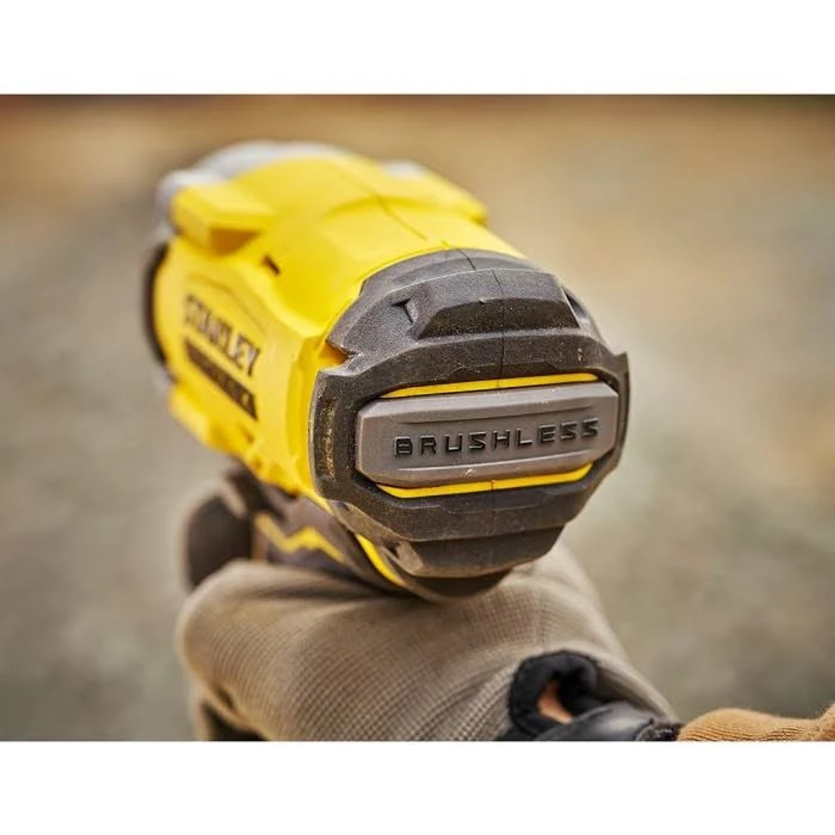 Ein gelbes und schwarzes Elektrowerkzeug mit dem Wort BRUSHLESS, gehalten von einer behandschuhten Hand.