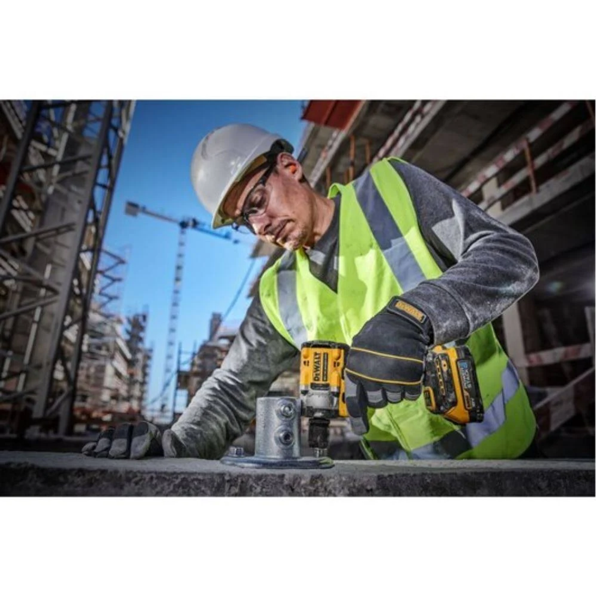 Un trabajador de la construcción usa una llave de impacto DeWalt en una estructura metálica, usando equipo de seguridad.