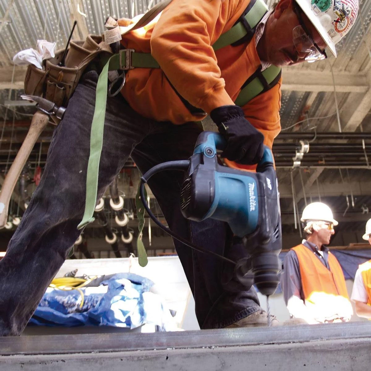 Trabajador de construcción con taladro. Usa equipo de seguridad y trabaja en estructura de hormigón.
