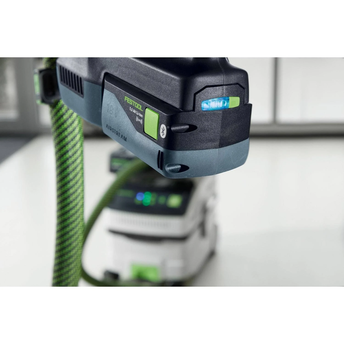 Un primer plano de una batería Festool 18V negra y verde con una luz.