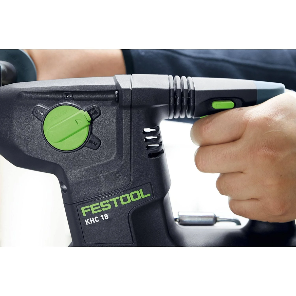 Taladro eléctrico negro y verde sostenido por una persona. El taladro tiene un interruptor verde y la marca es Festool.