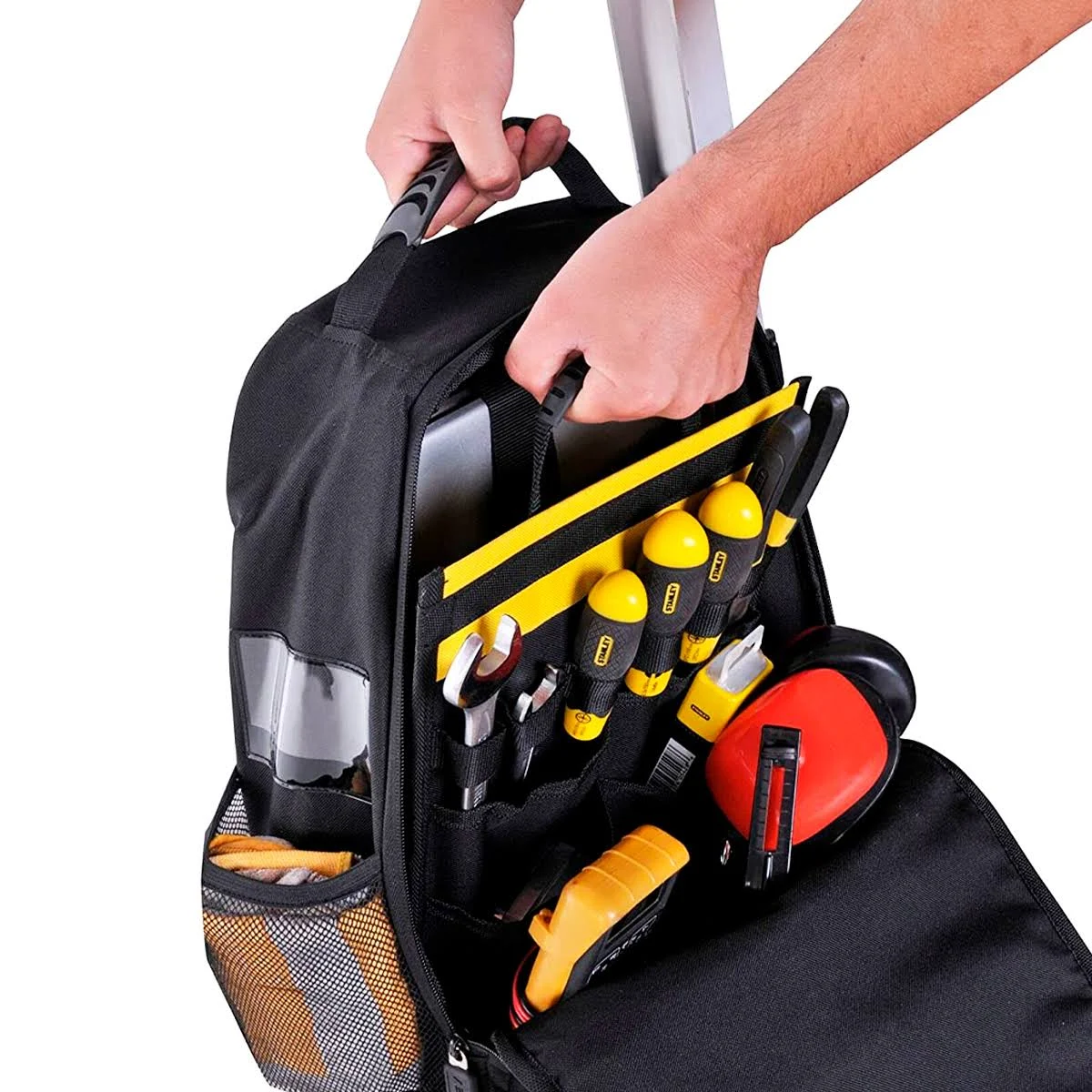 Persona che mette la mano in una borsa nera per attrezzi piena di attrezzi come cacciaviti, metro a nastro e protezione per le orecchie.